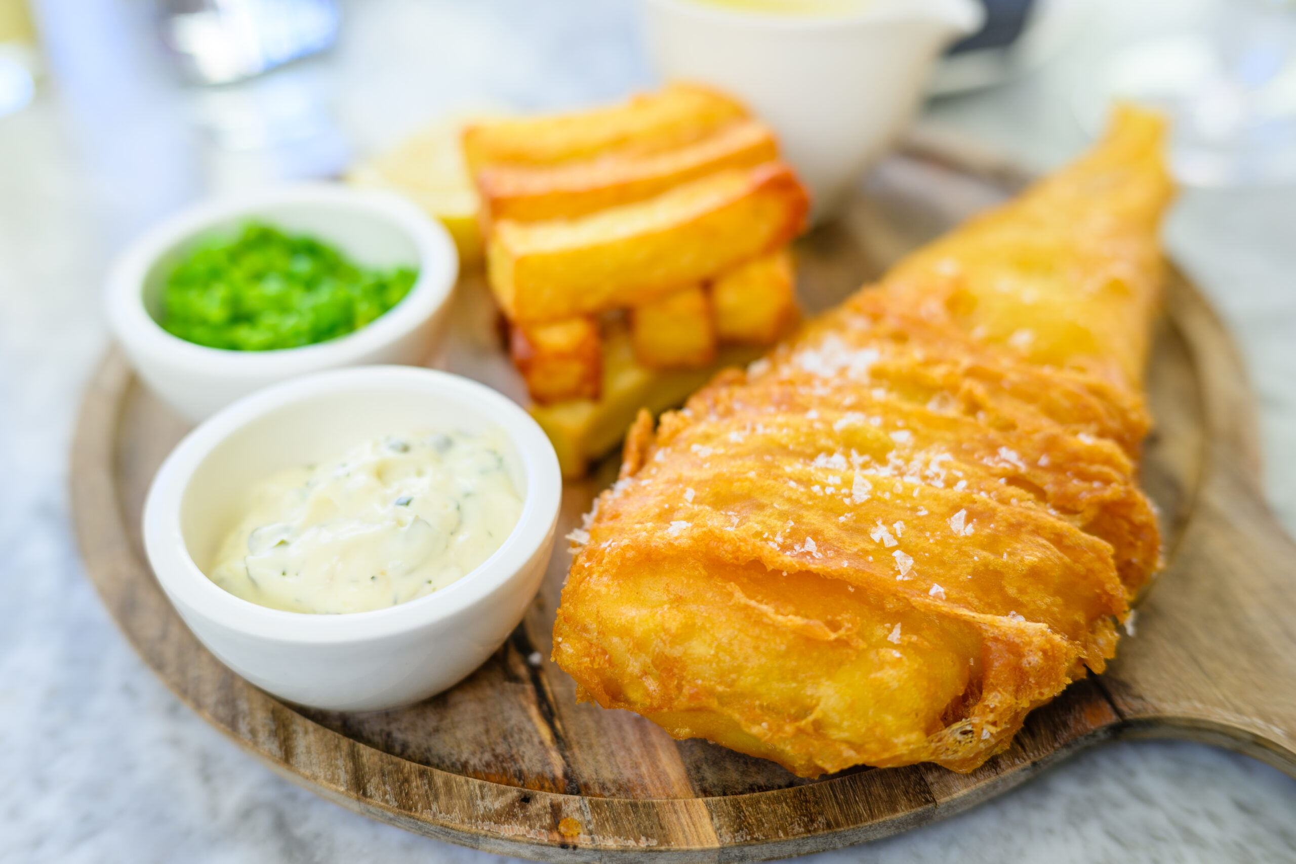 A Rustic Wooden Board Of Battered Fish And Chips