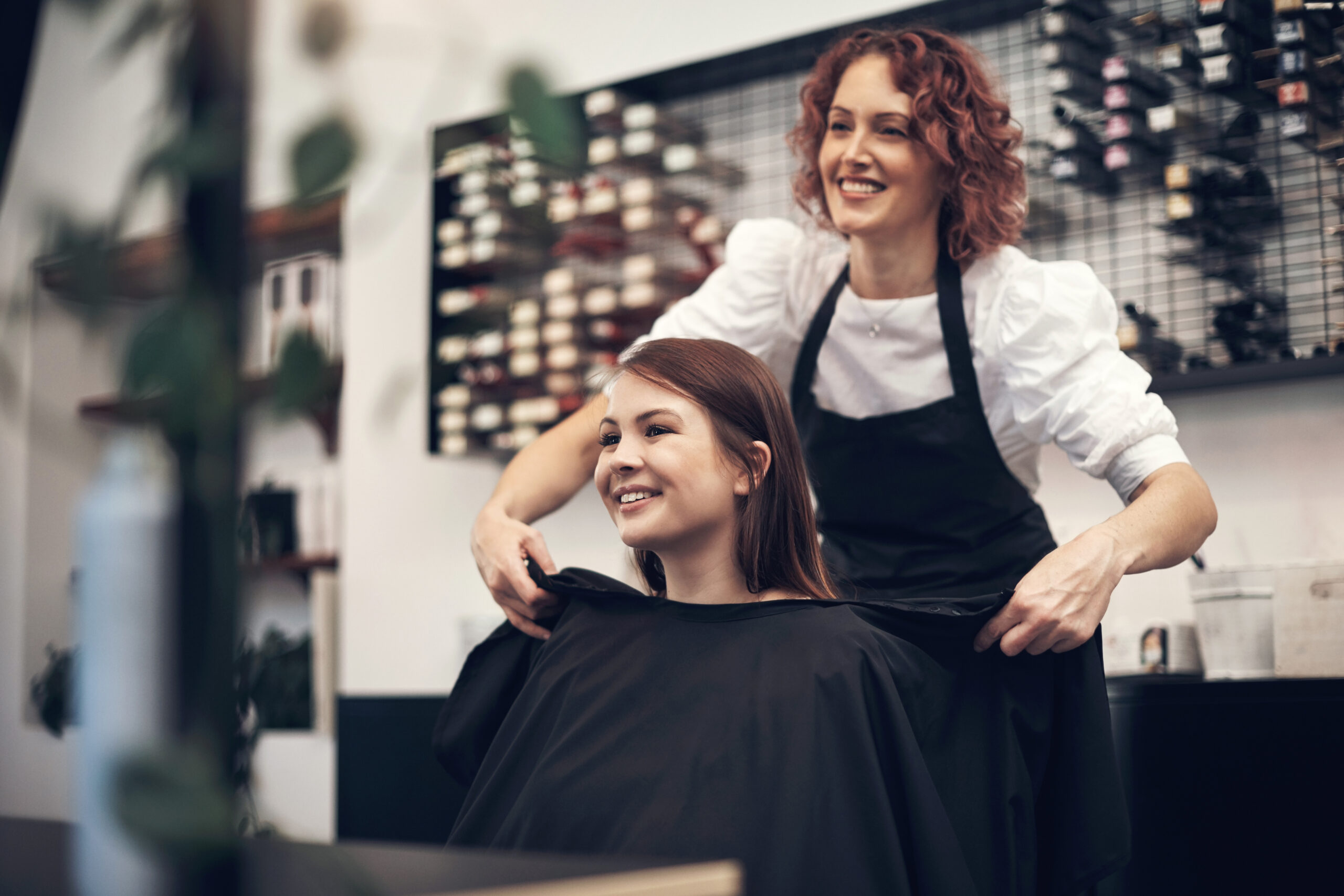 Hairdresser Putting Cape On Client In aSalon