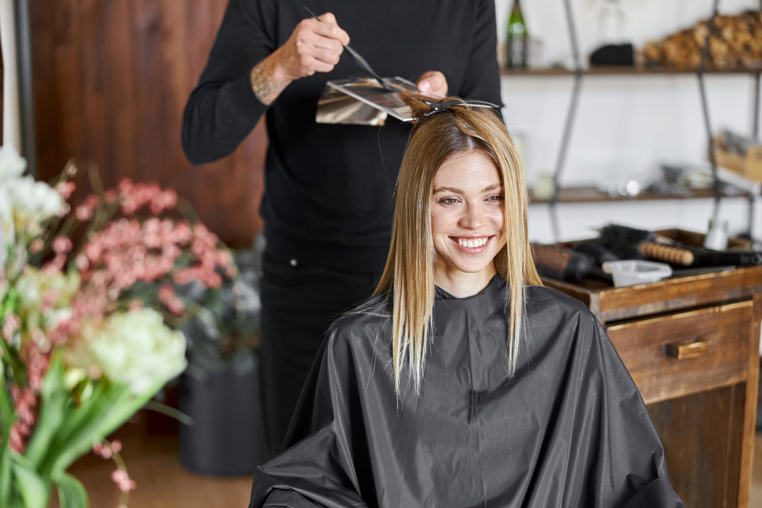 Woman Smiling While Getting Hair Styled In a Salon 