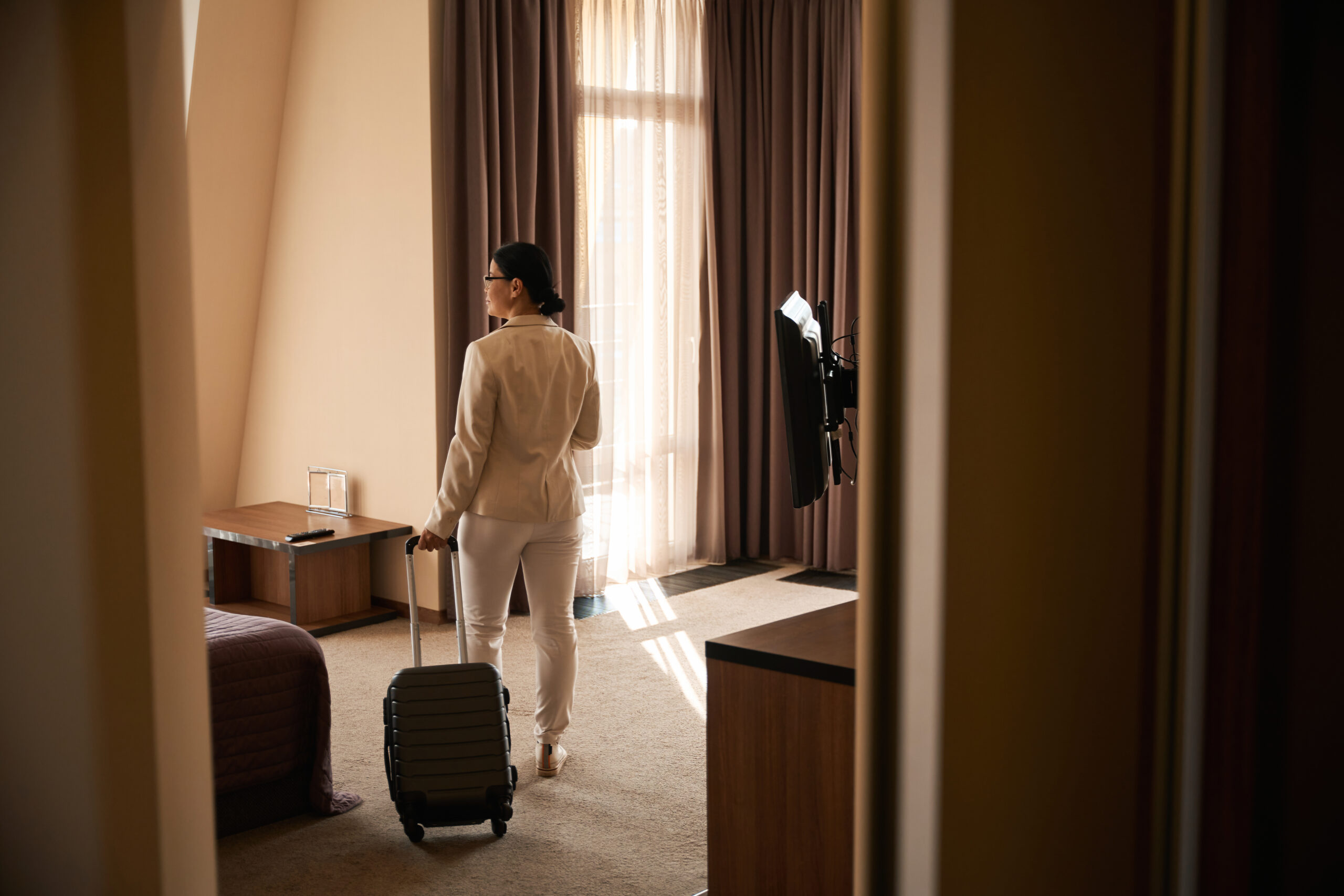 Female Tourist With Baggage Looking Around In Hotel room 