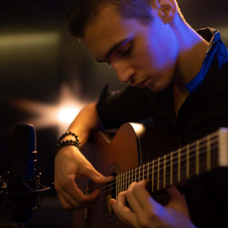 Focused Young Man Playing Guitar With Microphone
