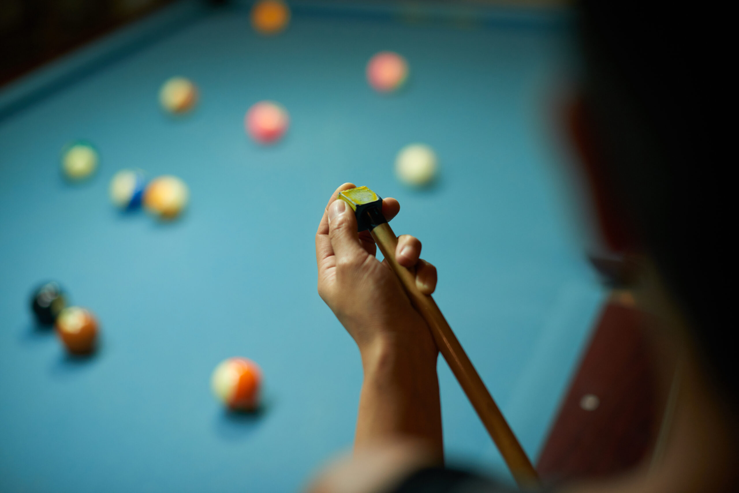 Hands of player chalking cue and waiting for their turn