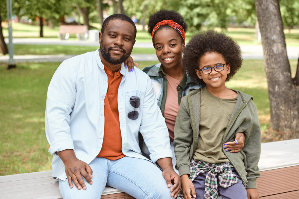 Family Sitting On Bench In ParK