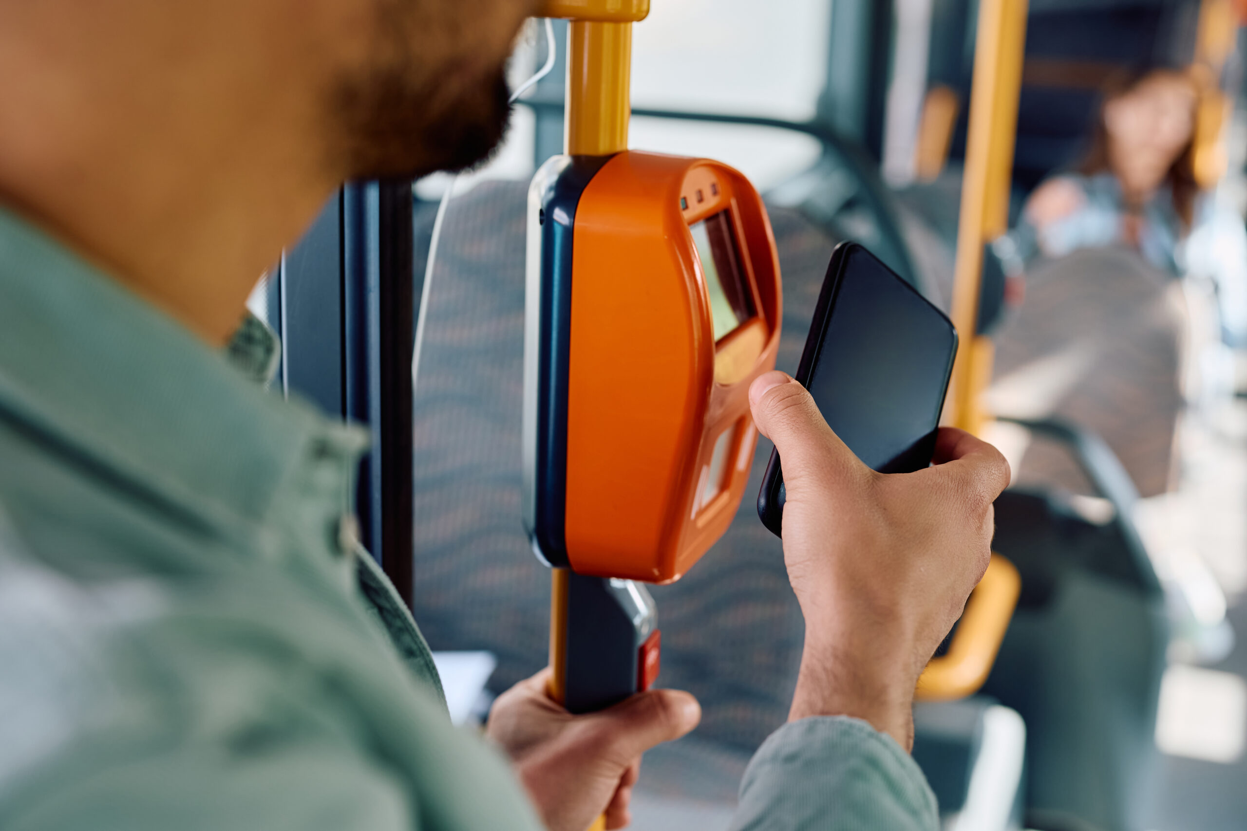 Close up of man paying with smart phone while onboarding in public transport.