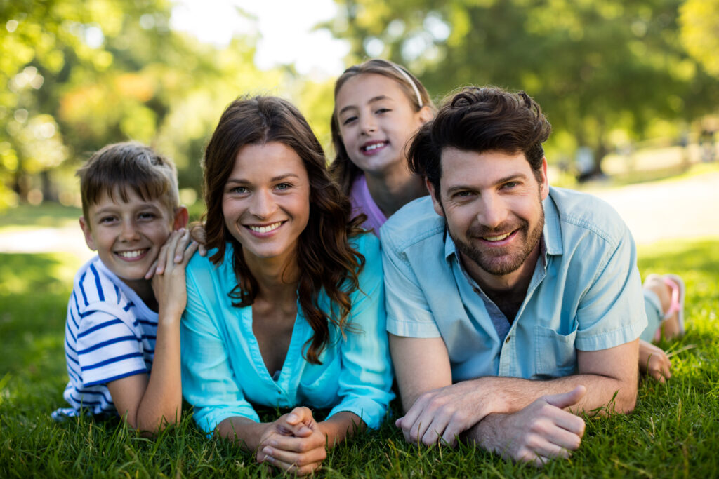 Happy Family Lying On Grass In Park