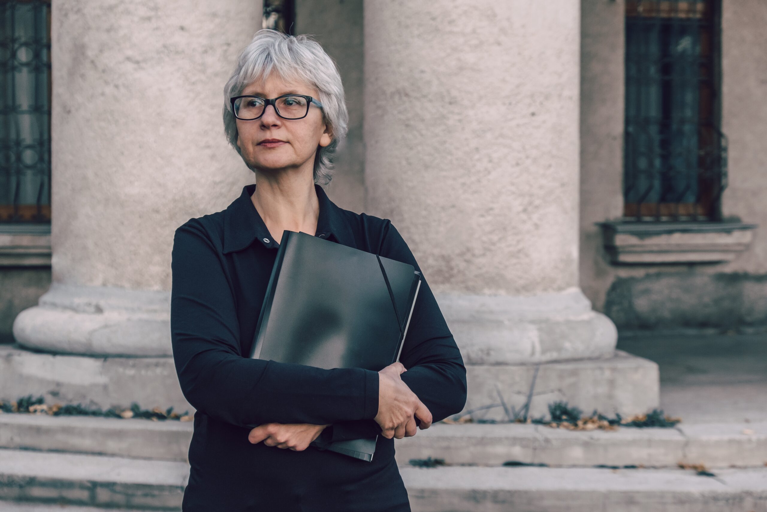 Professional Woman Standing Near A Column With a Document