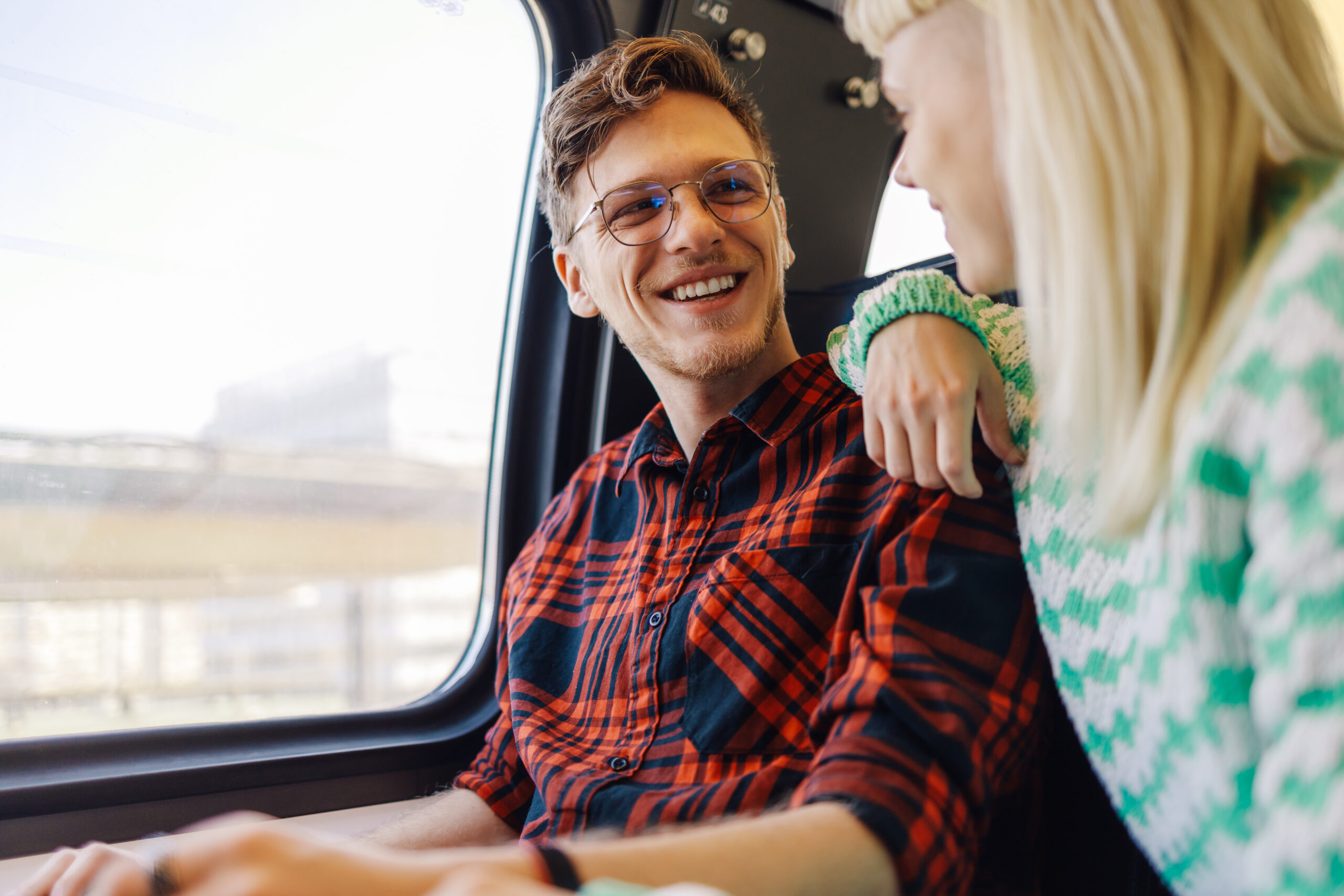 Happy passengers sitting in train near window and enjoying journey. 