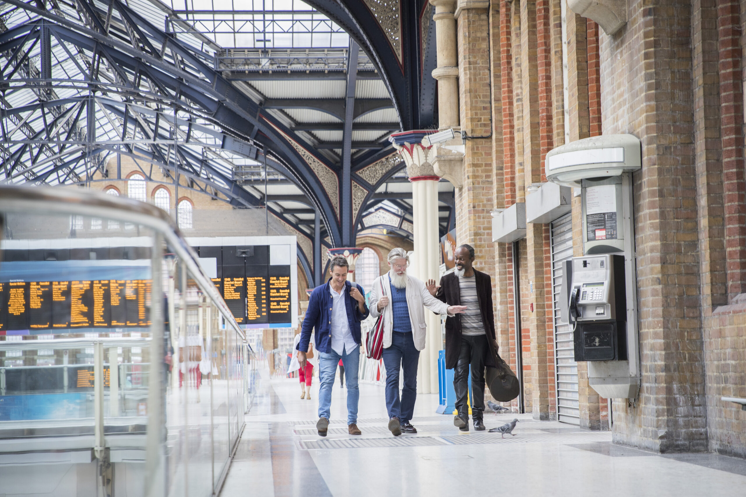 Three mature men at train station, walking together