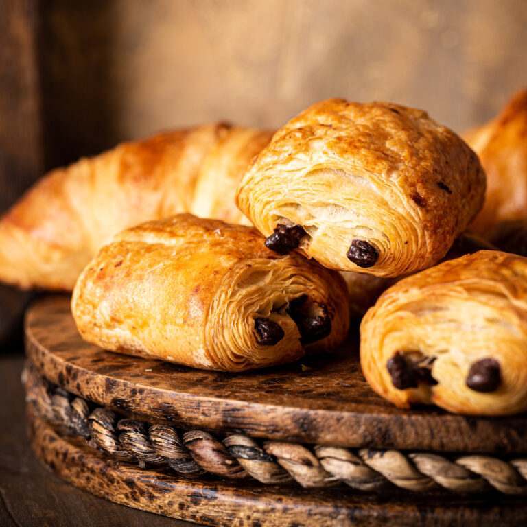 Delicious Chocolate Croissants and Croissant on Wooden Board at one of the best bakeries in Brighton