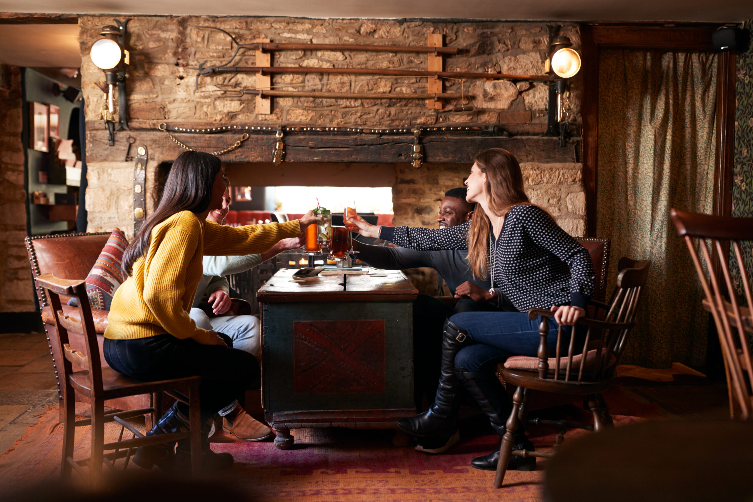 Group Of Friends Making Toast As They Meet For Lunchtime Drinks In Traditional English Pub