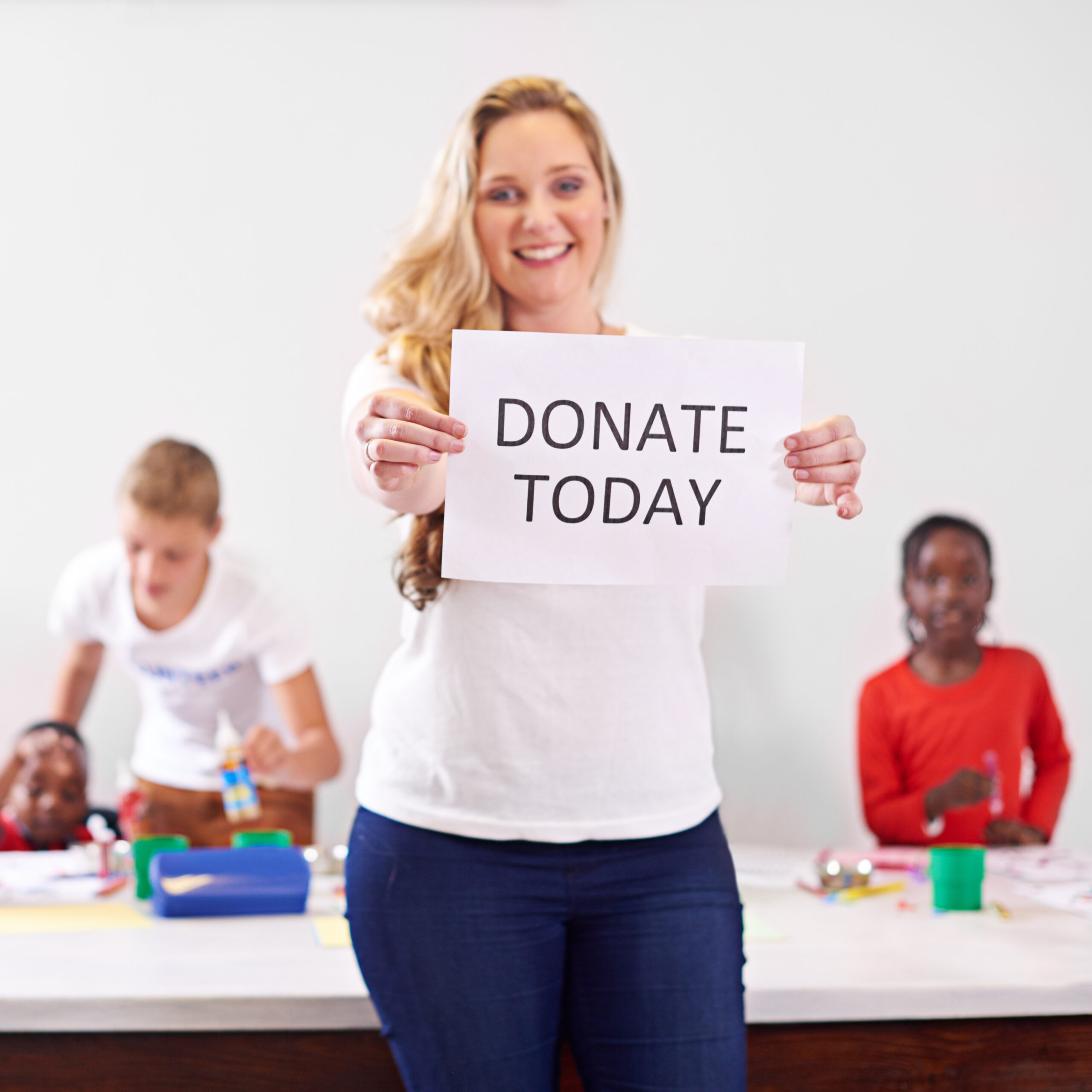 A woman holding up a sign saying "donate now" at one of the charities in Brighton