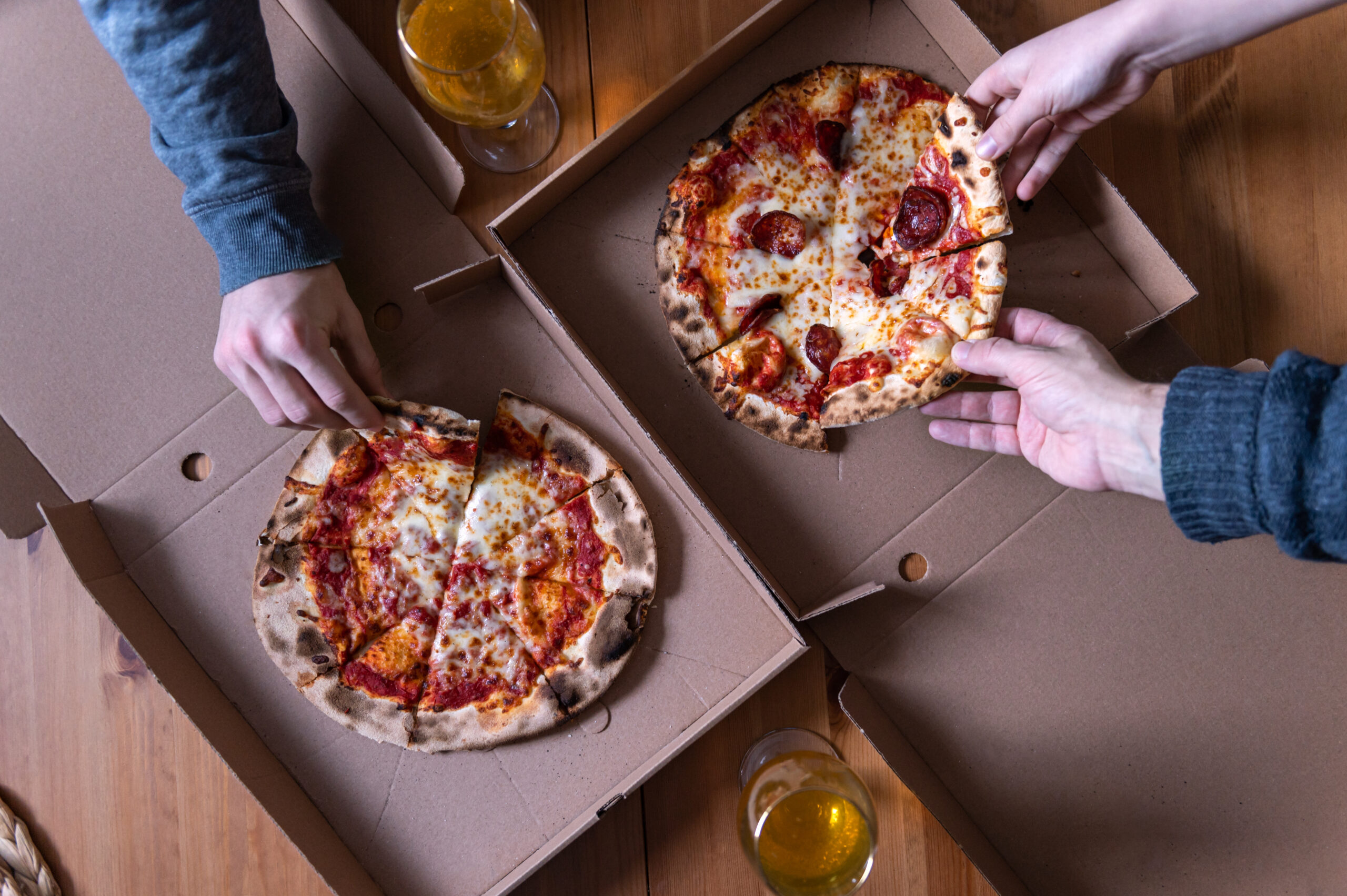 Takeaways in Brighton- pizzas in boxes margherita and pepperoni. Hands of several people are taking pieces