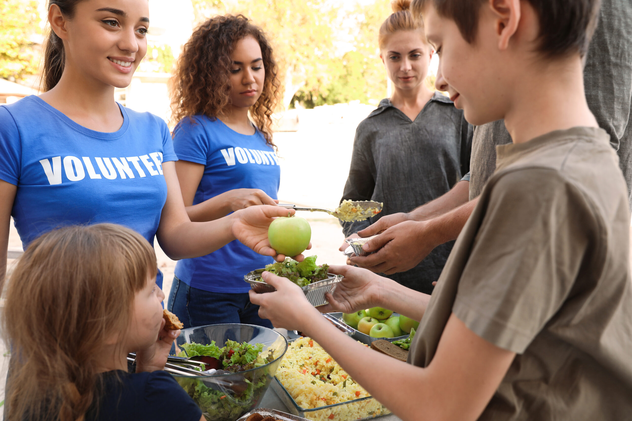 Volunteers Providing Food To Those In Need Outdoors 