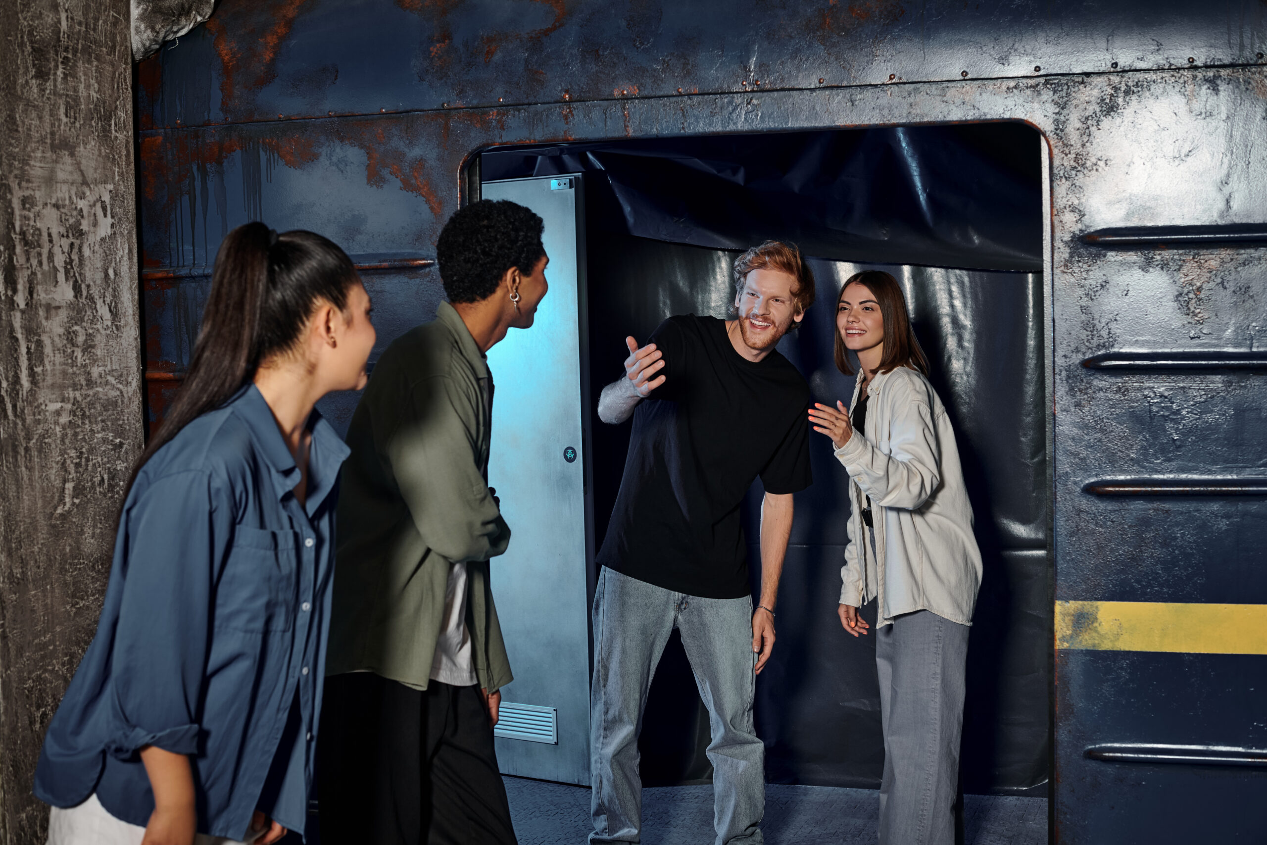 Cheerful Young Man Gesturing And Inviting Friends in to one of the escape rooms in Brighton