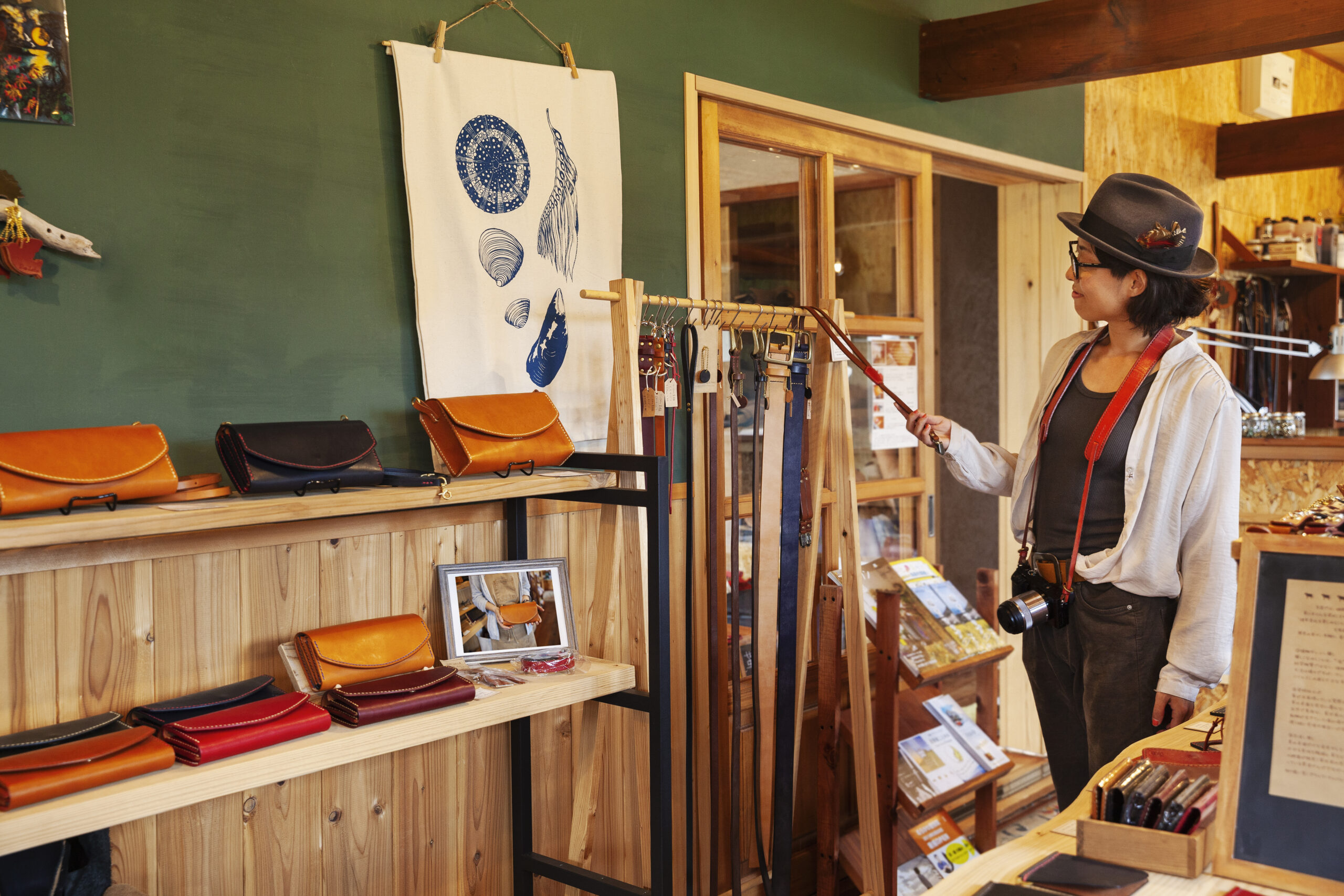 Woman wearing hat and glasses browsing merchandise in a leather shop.