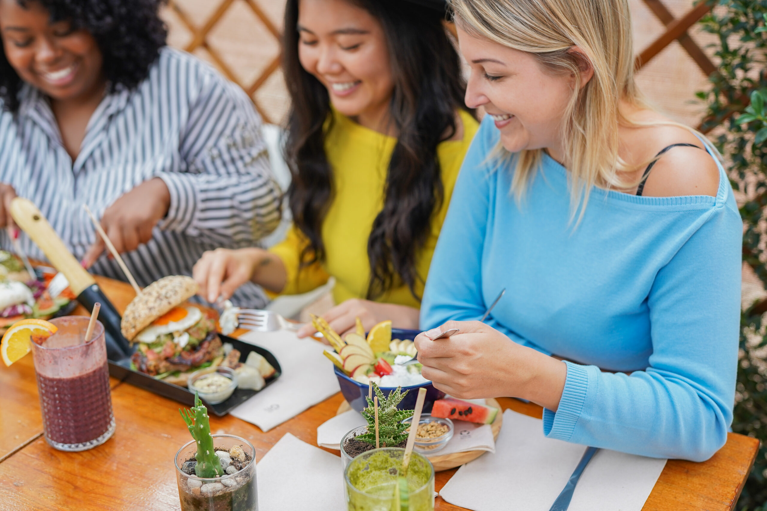 Women eating a healthy brunch at a restaurant terrace during spring season