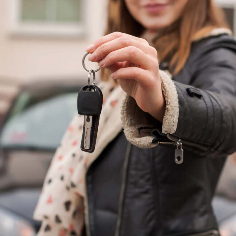 Driving lessons in Brighton: Young Woman Holding Car Keys in Suburban Setting