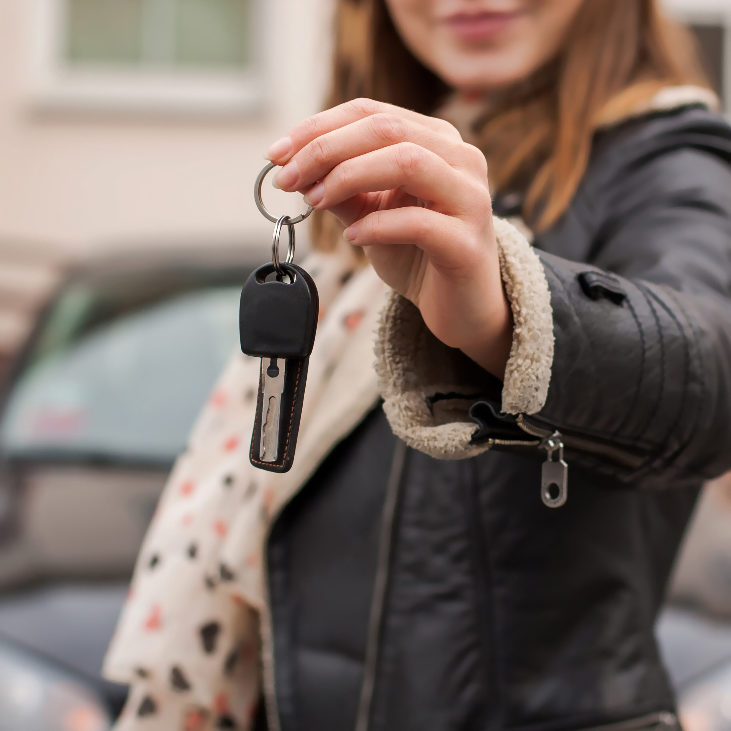 Driving lessons in Brighton: Young Woman Holding Car Keys in Suburban Setting