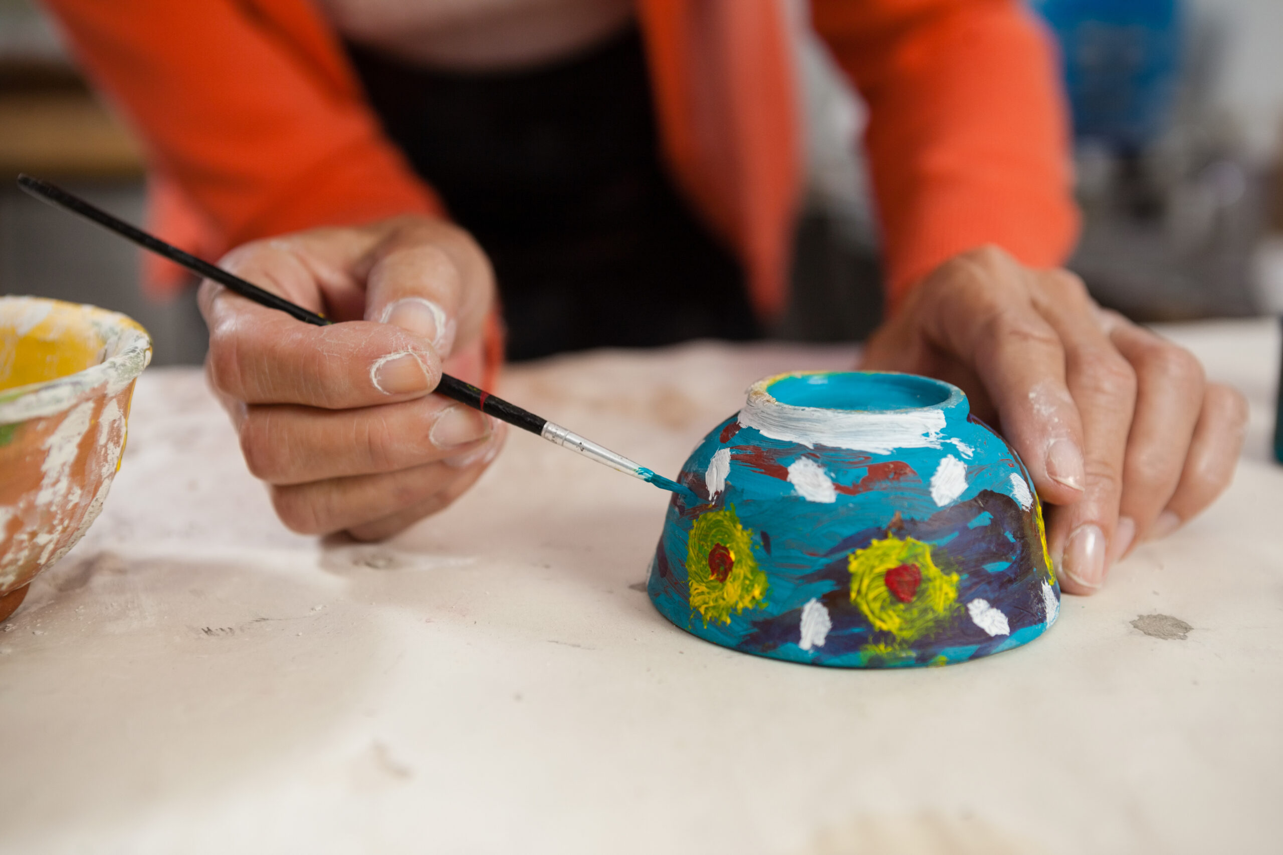 Hands Decorating Colorful Bowl With Paintbrush 