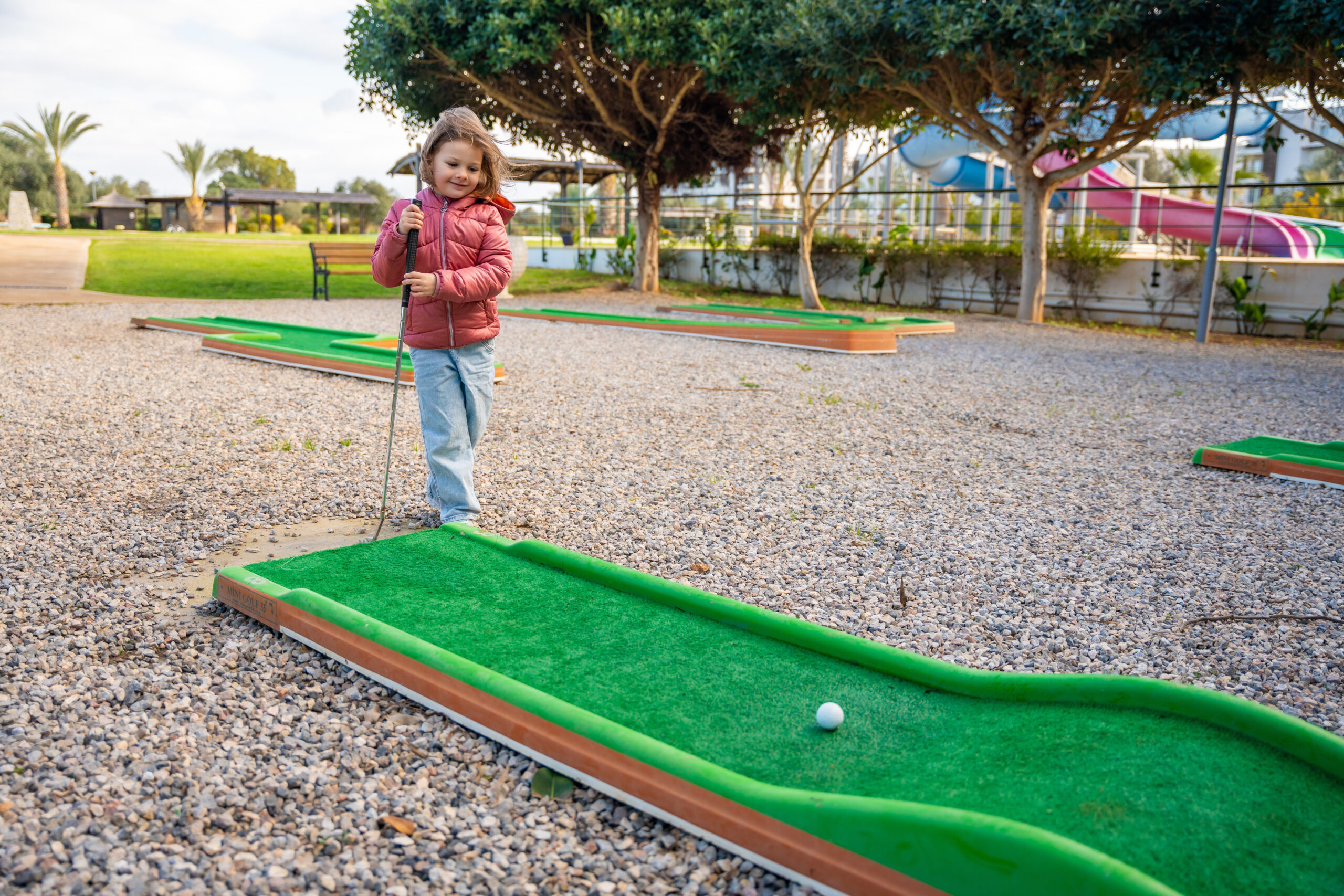 Little girl playing mini golf outdoors