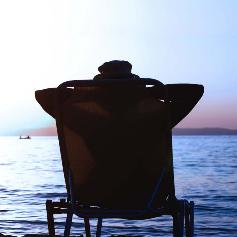 Silhouette Of Woman With Hat Sitting On Sunbeds