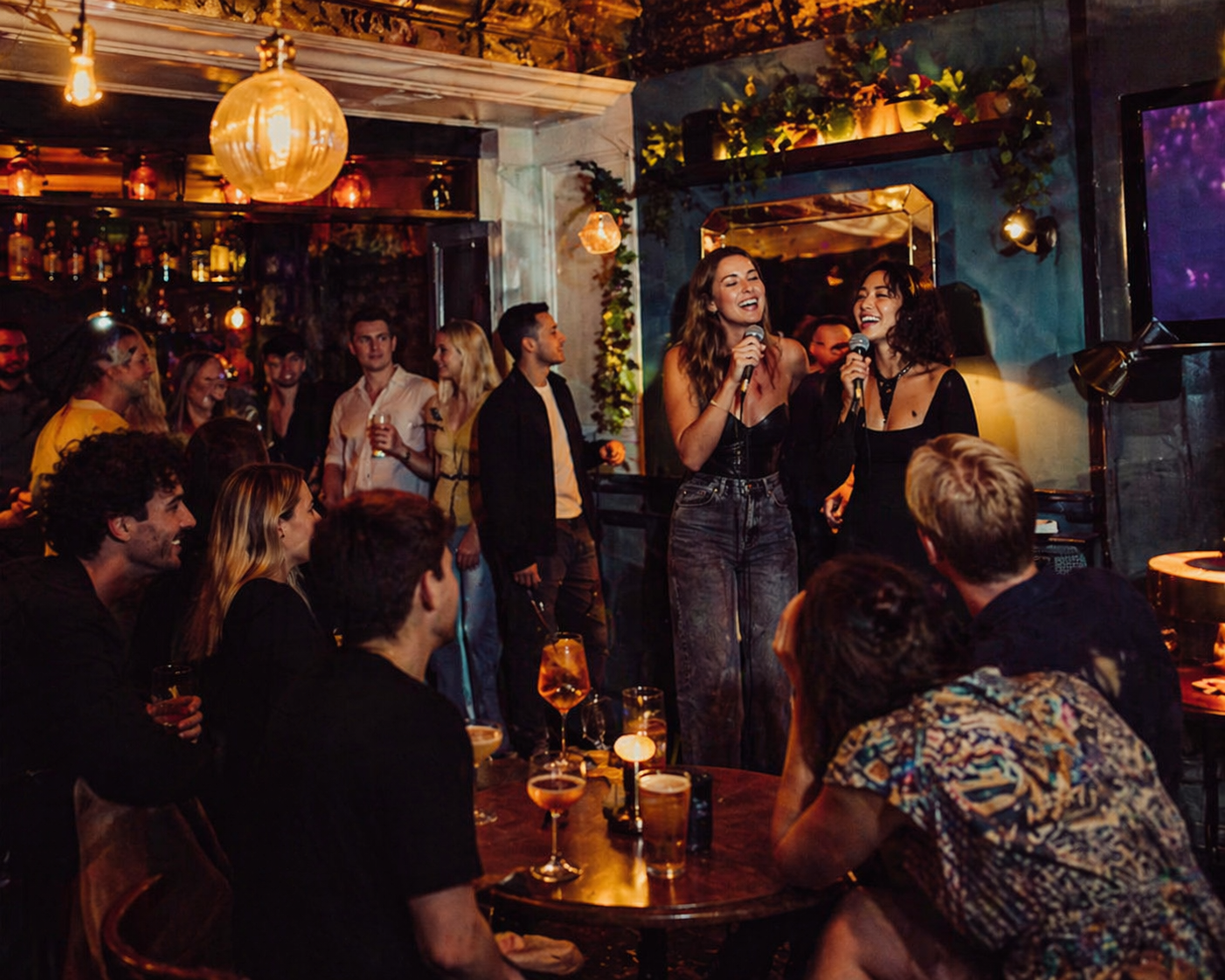 People doing Karaoke in Brighton with a small karaoke setup, upbeat crowd, microphones, cocktails and pints