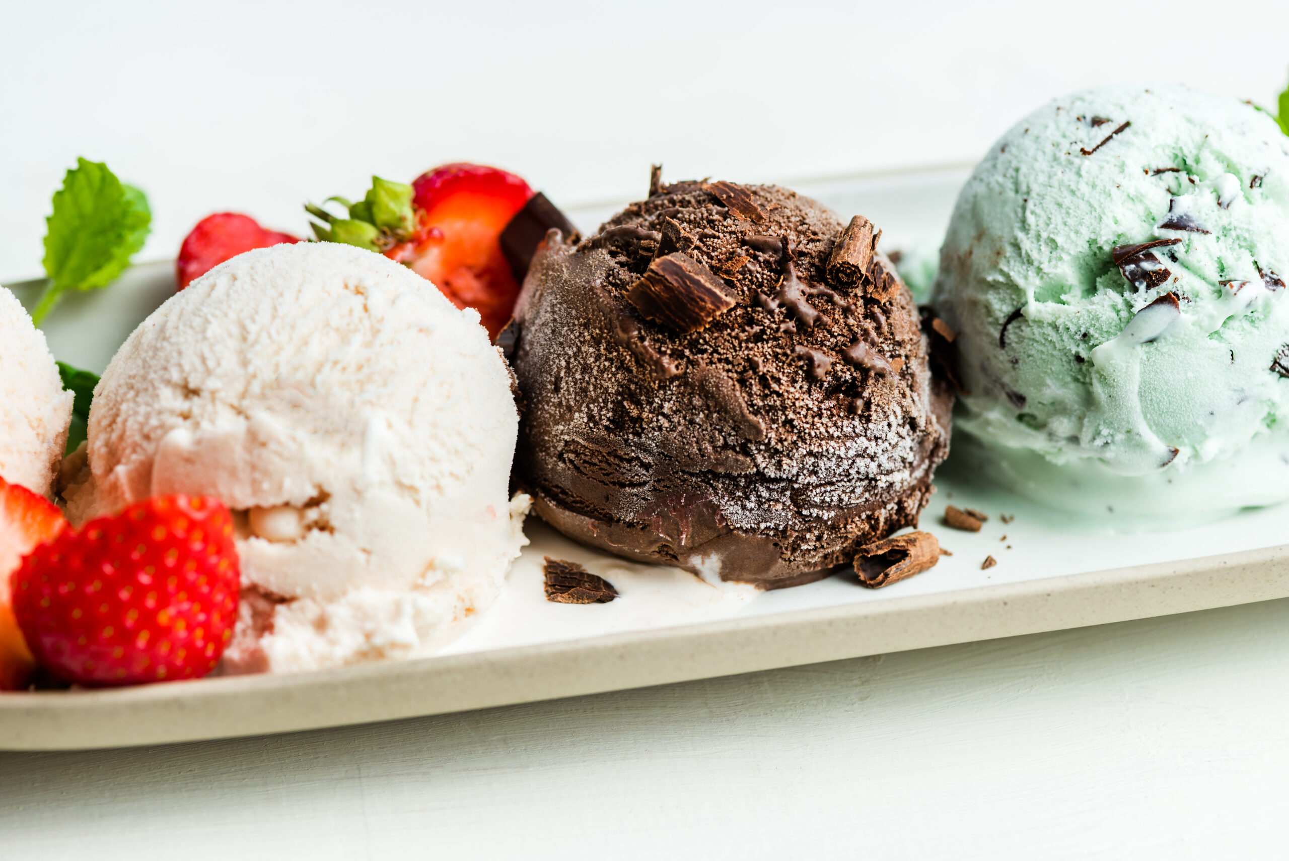 Selection of different ice cream scoops such as mint, chocolate and strawberry on the oval plate