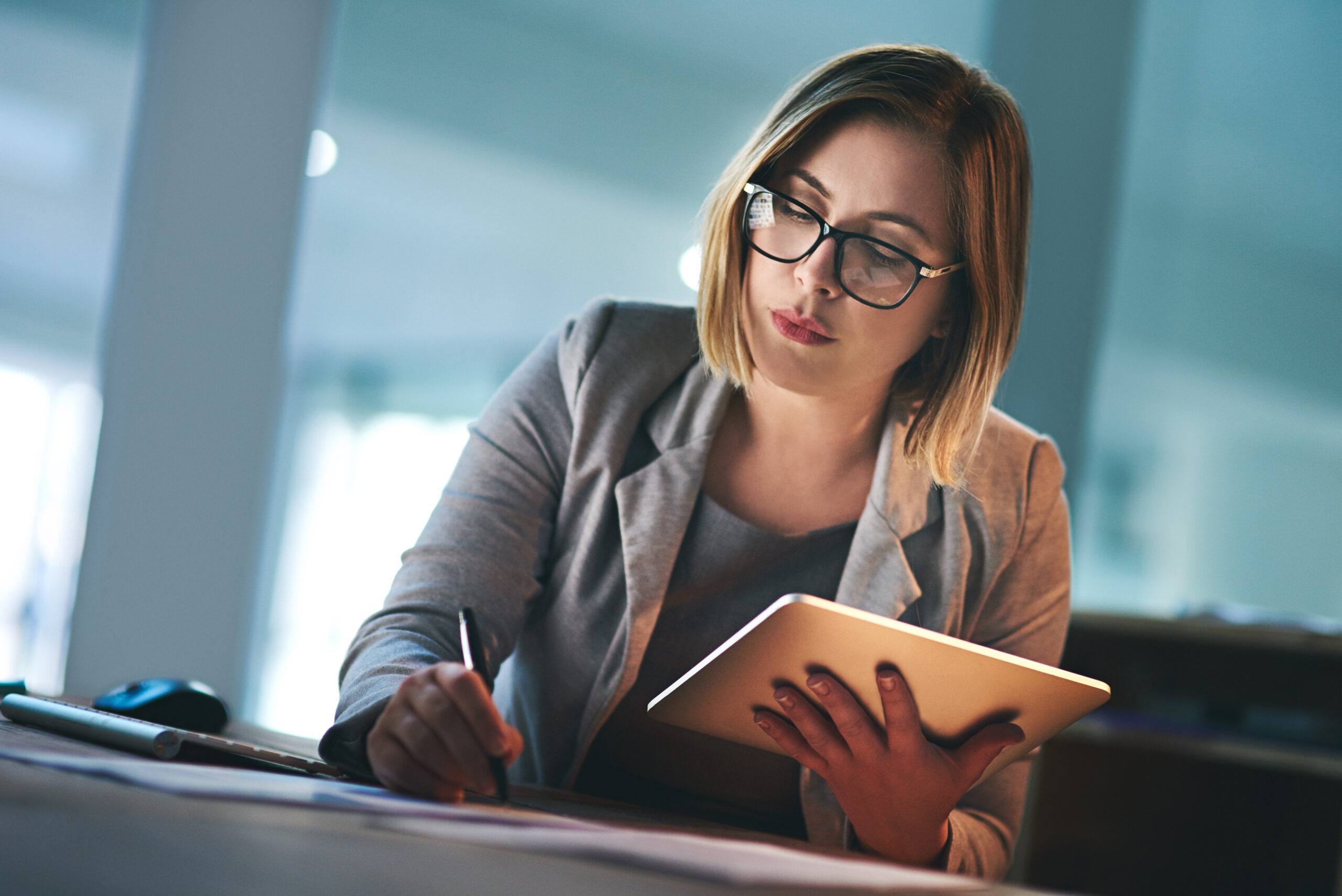 Shot of a young businesswoman working late on a digital tablet in an office.