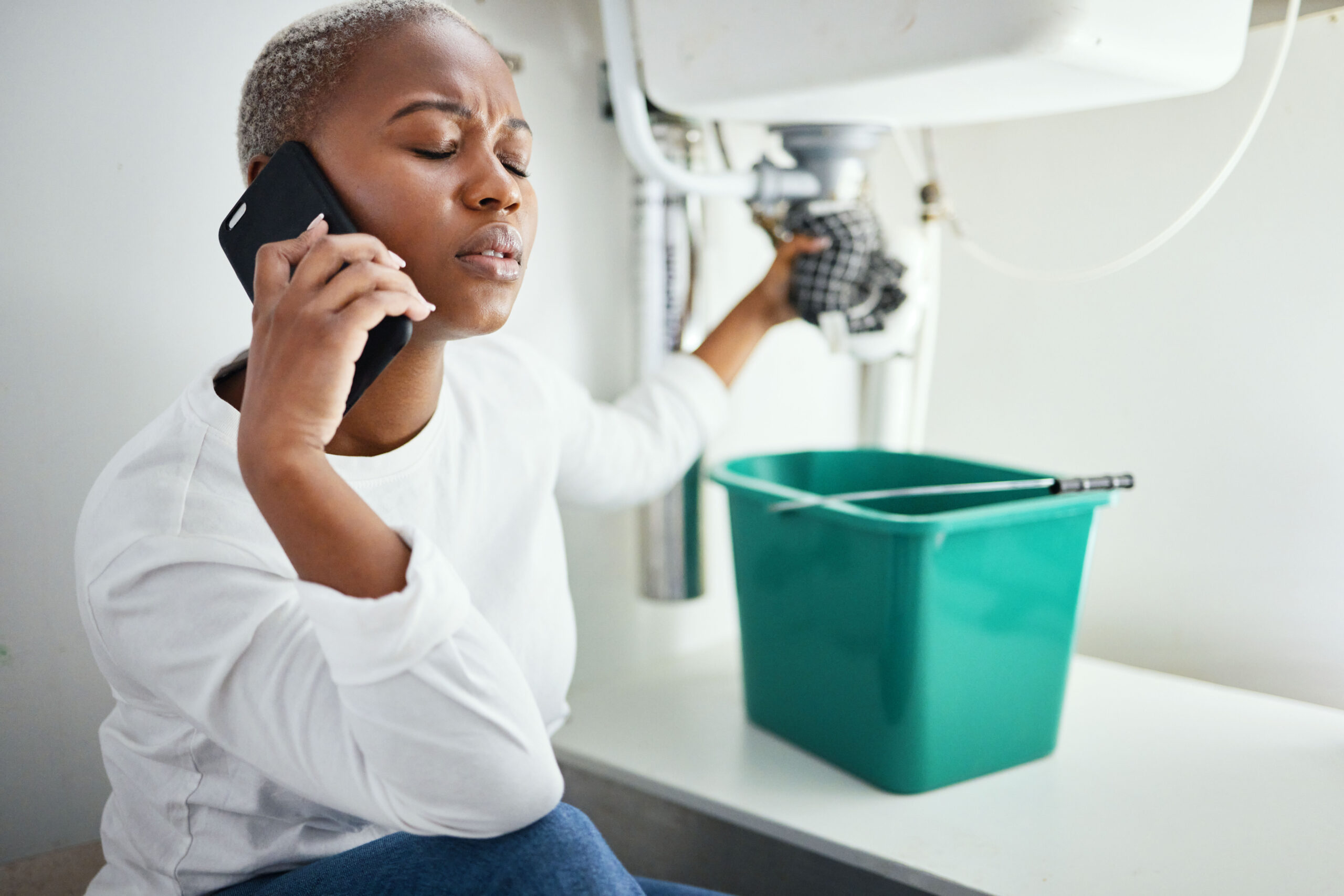 Worried Woman Dealing With A Plumbing Emergency on the phone to emergency plumbers in Brighton