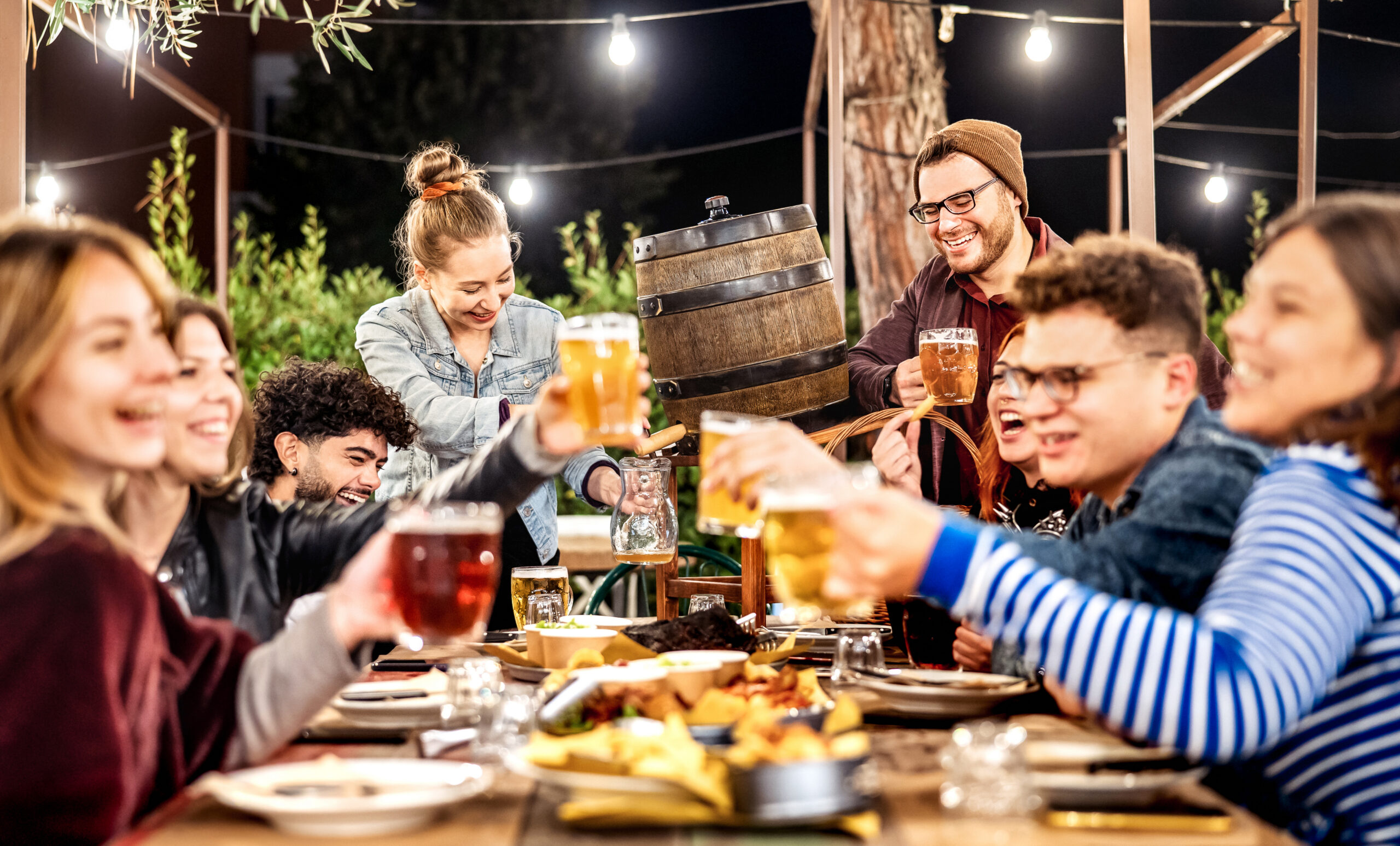 Young men and women having fun drinking out at beer garden 