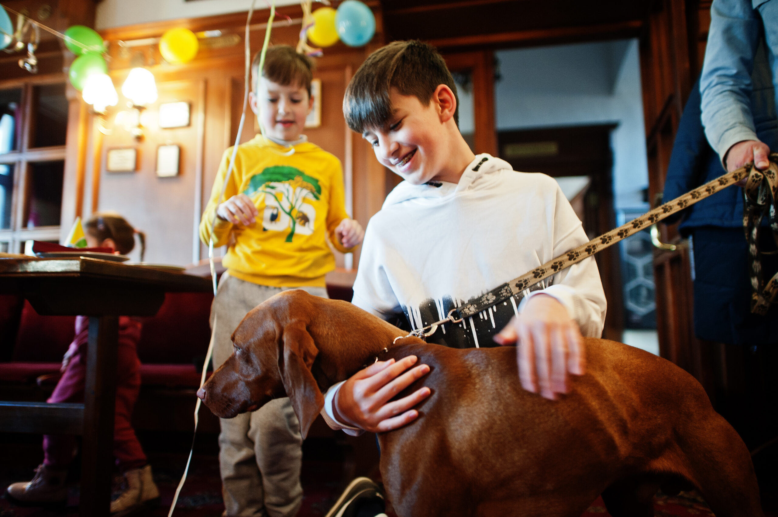 Children at a birthday party playing with a dog.