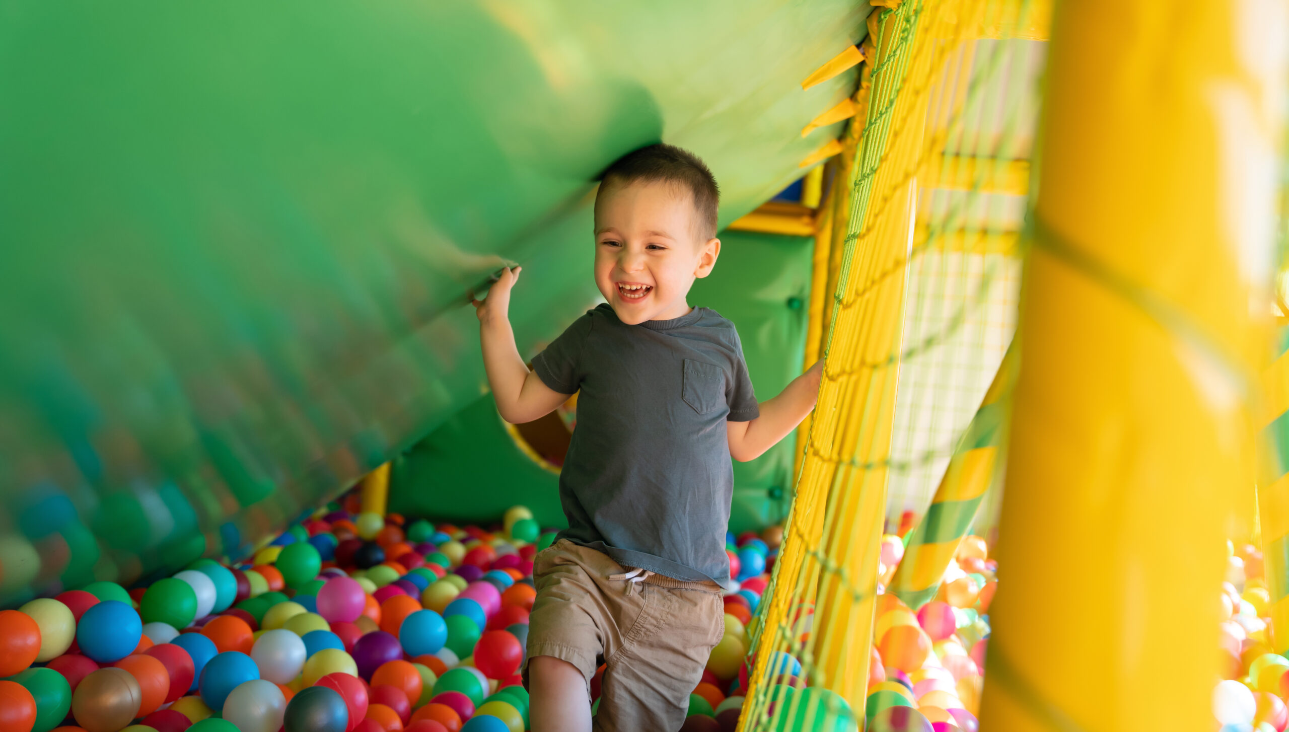 Cheerful Young Child Playing in Colourful Ball Pit
