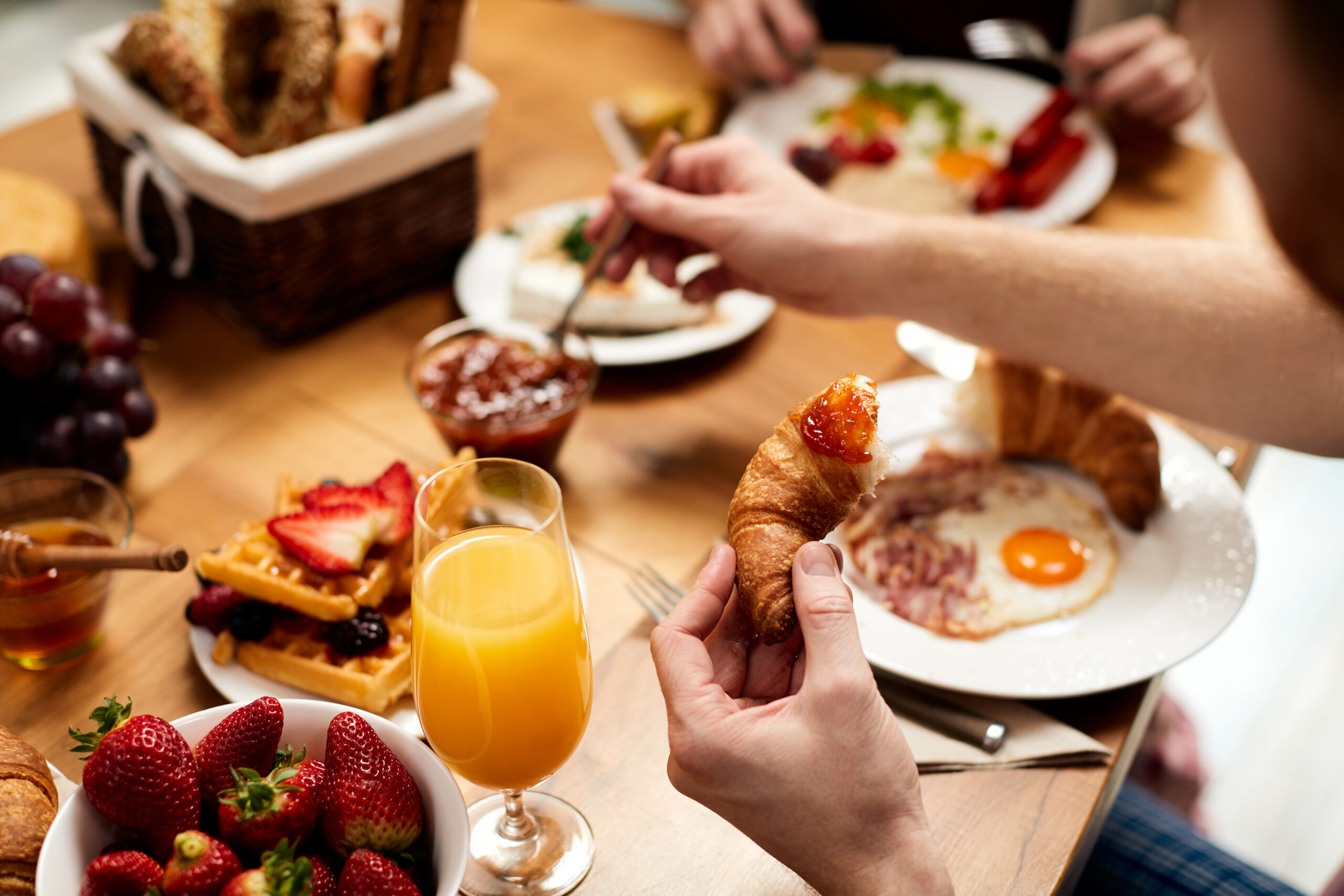 Close-up of man having croissant with jam while eating brunch.