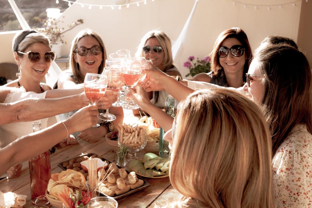 Group of cheerful women in friendship enjoying party for birthday. Wooden table. 