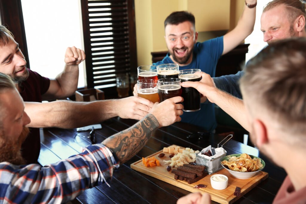 Friends clinking glasses with beer in pub