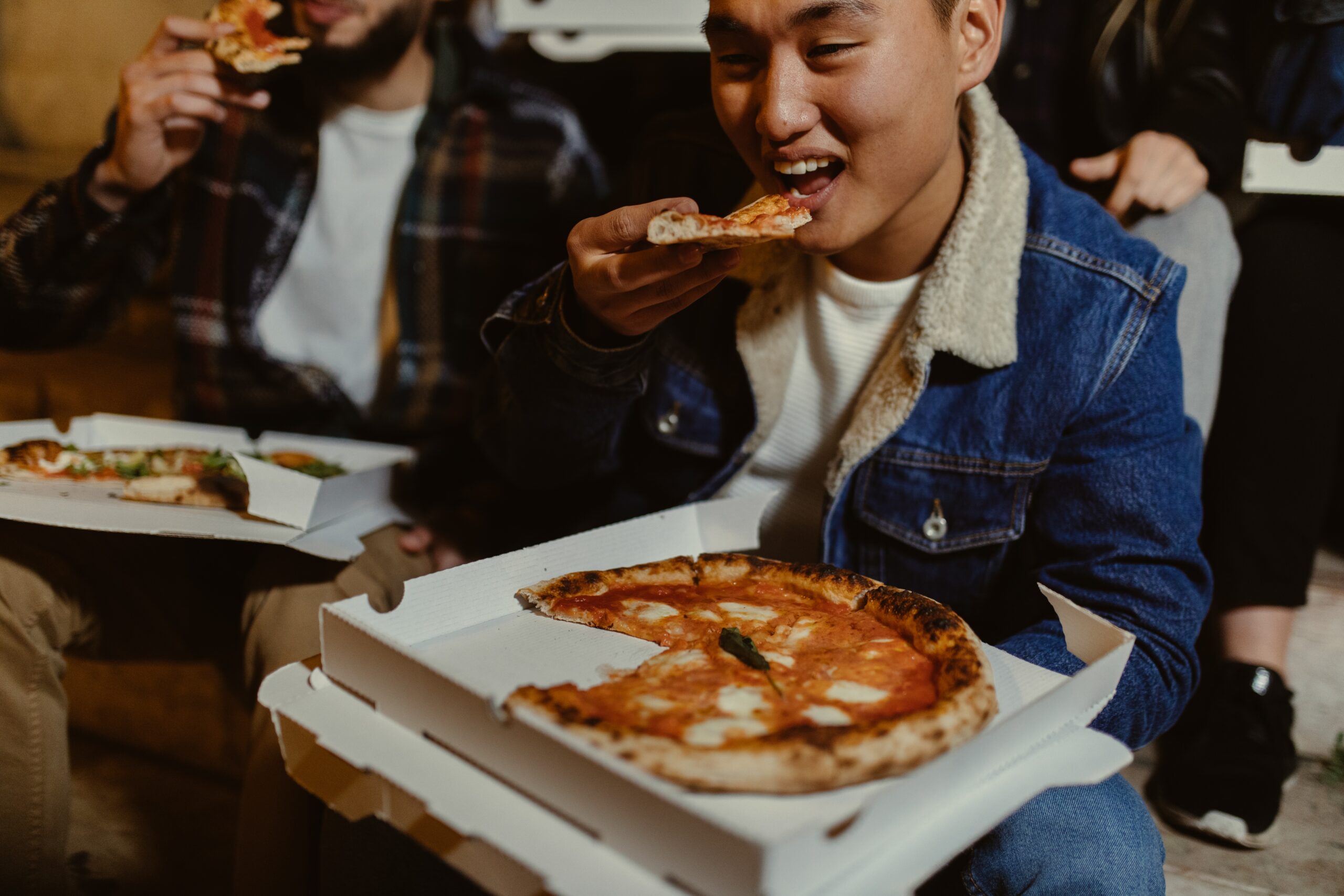 Friends Eating Pizza Together Outdoors At Night 