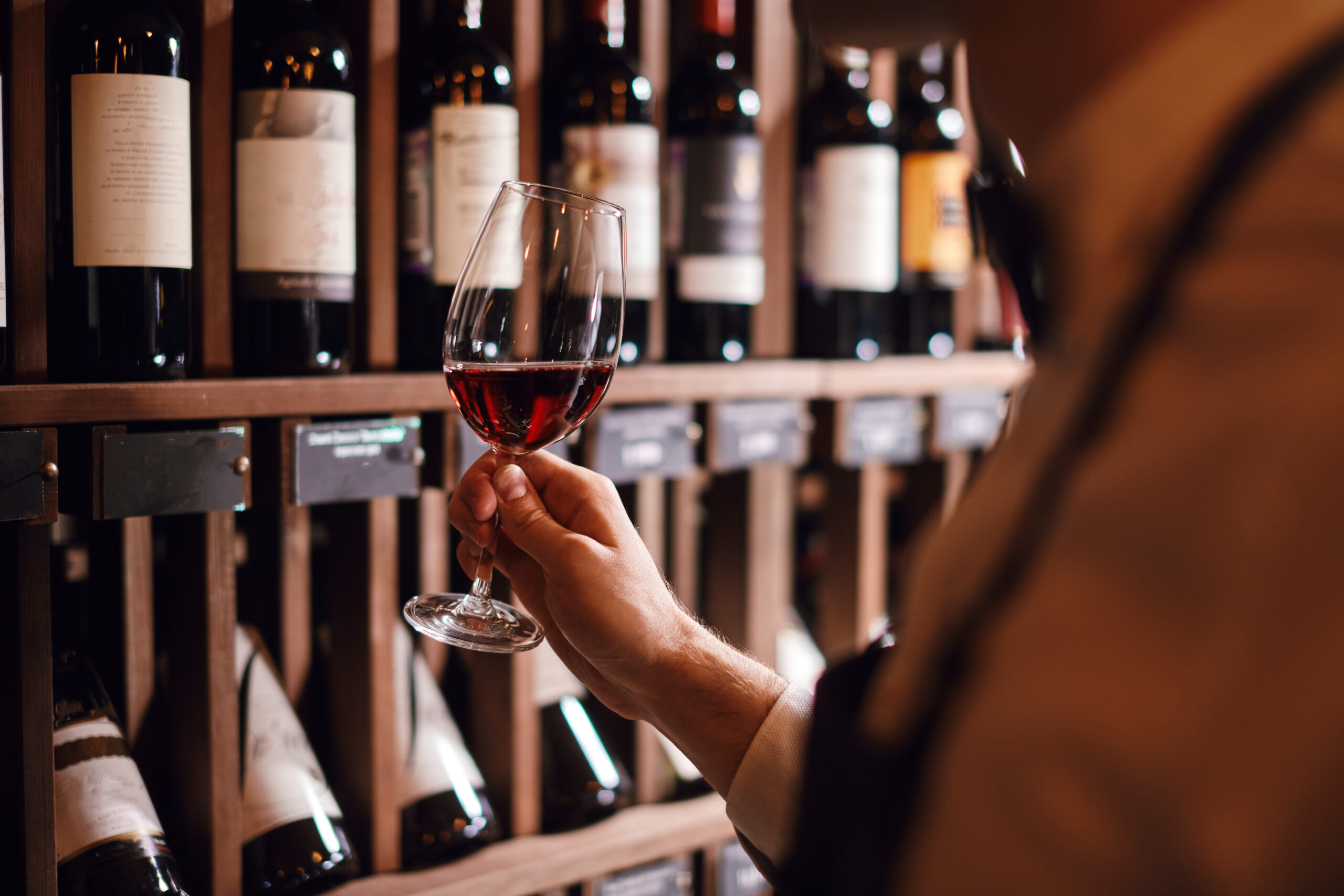 Man Holds Glass Of Red Wine at one of the wine bars in Brighton