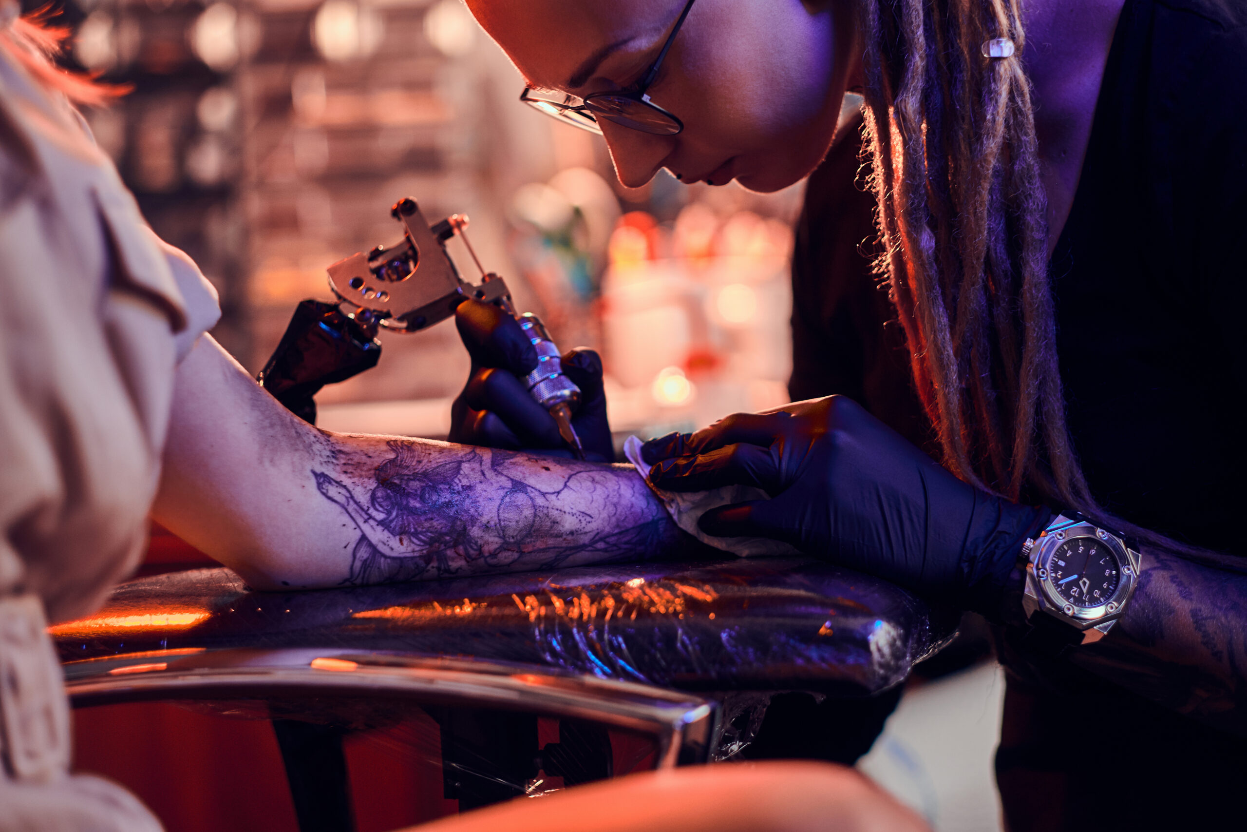 Process of creating new tattoo for young woman by experienced tattoo artist at studio.