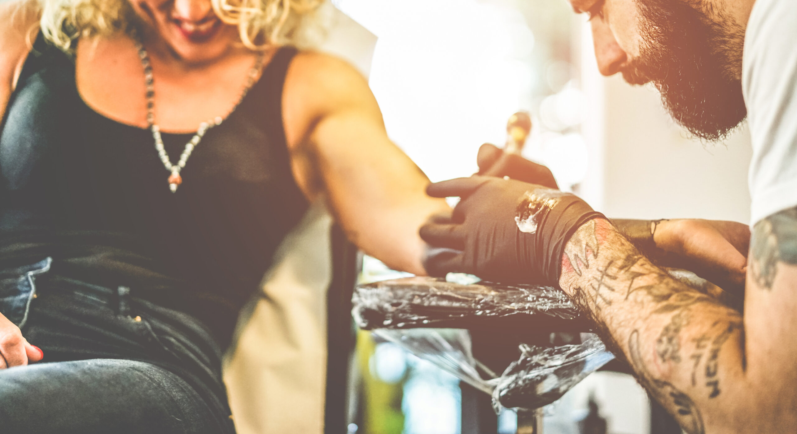 Process of creating new tattoo for young woman by expirienced tattoo artist at studio.