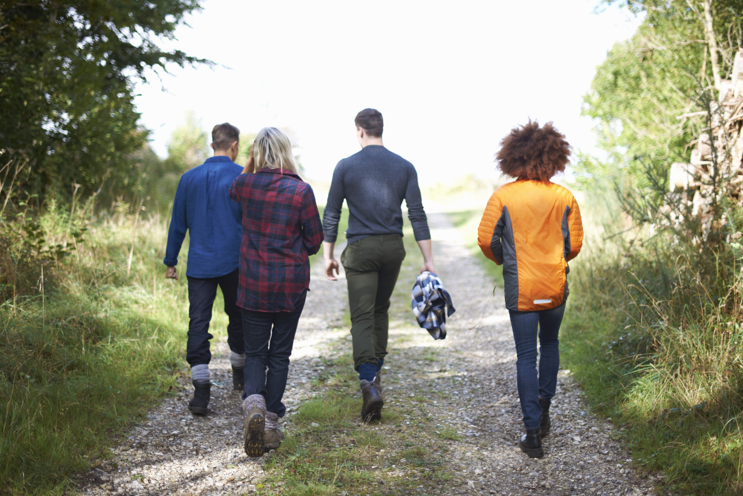 Rear View Of Friends Walking On Dirt Track