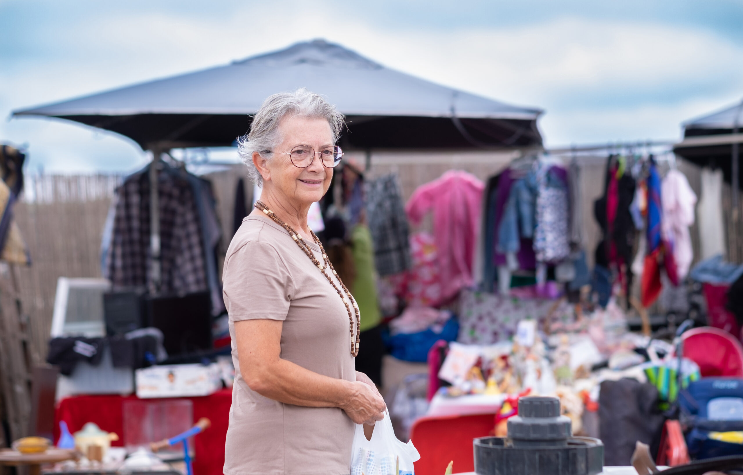 Senior woman at the flea market looking for second hand clothes.
