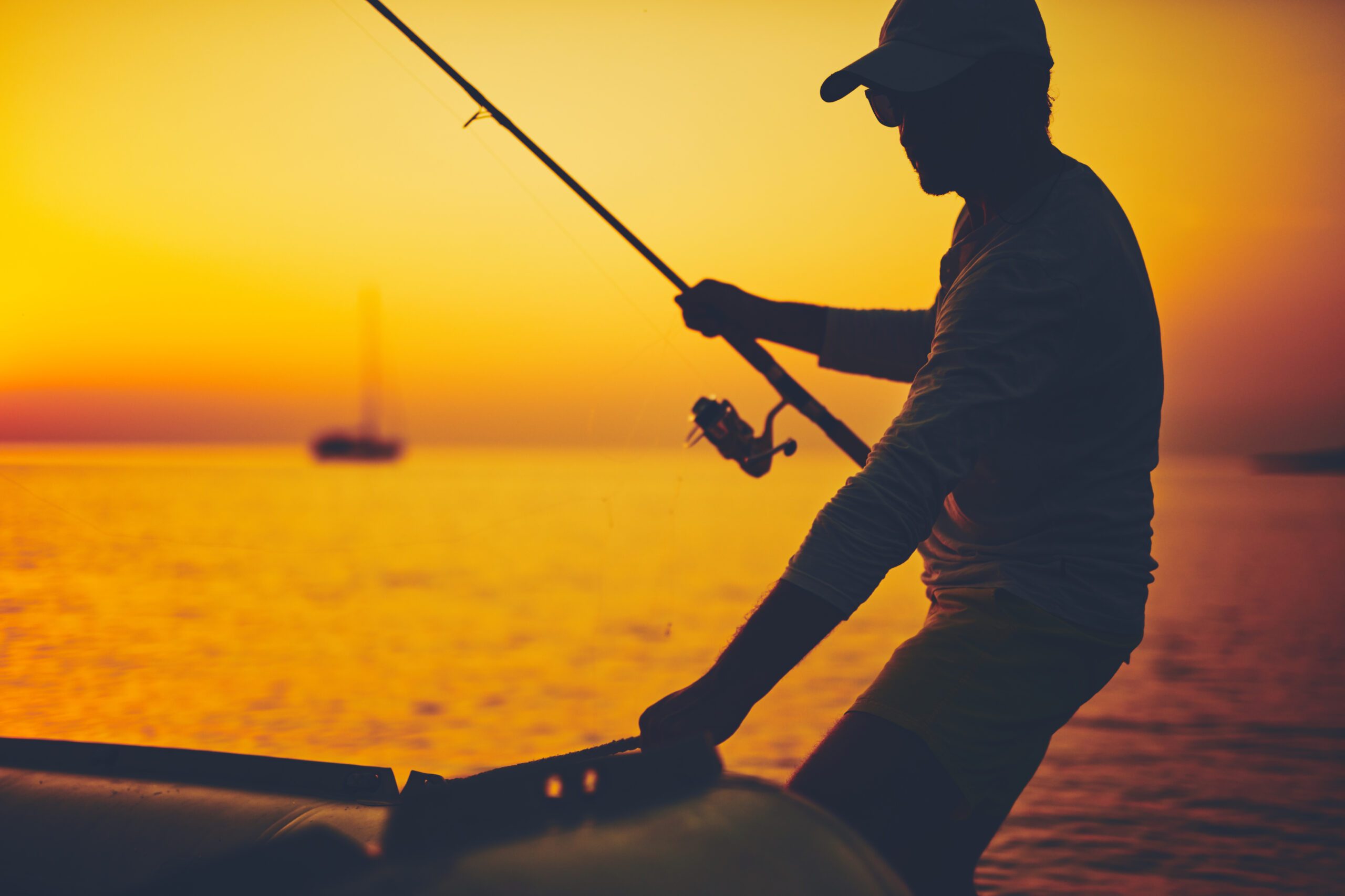 Silhouette Of A Fisherman Fishing In Sunset Time