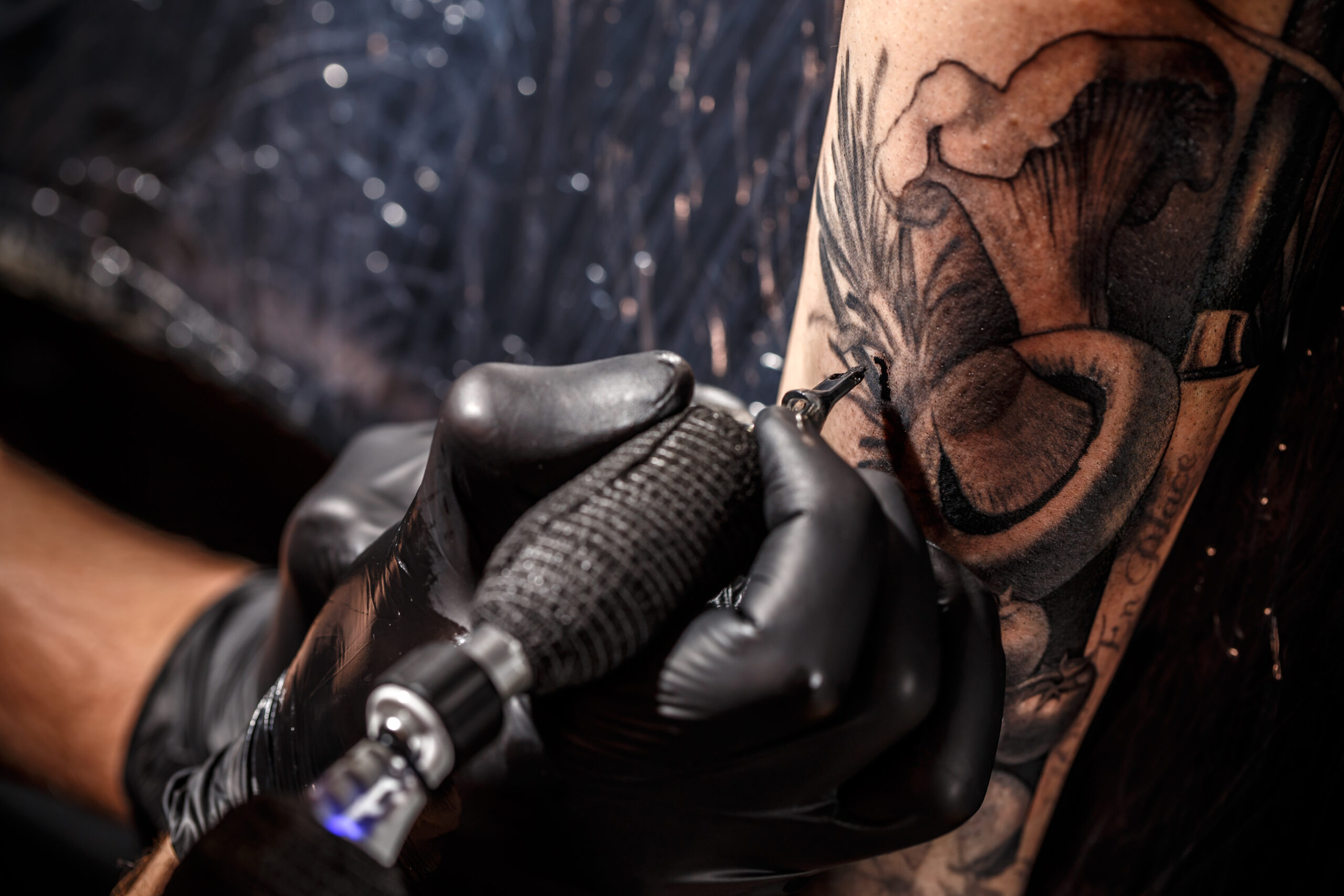 Close up image of the tattoo artist makes a tattoo on a mans arm at one of the tattoo studios in Brighton.