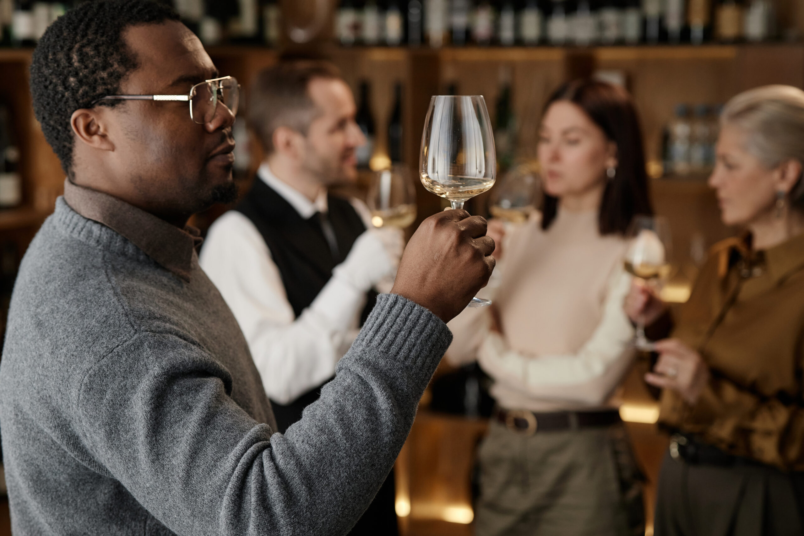 Adult man holding wine glass and examining colour while standing 
