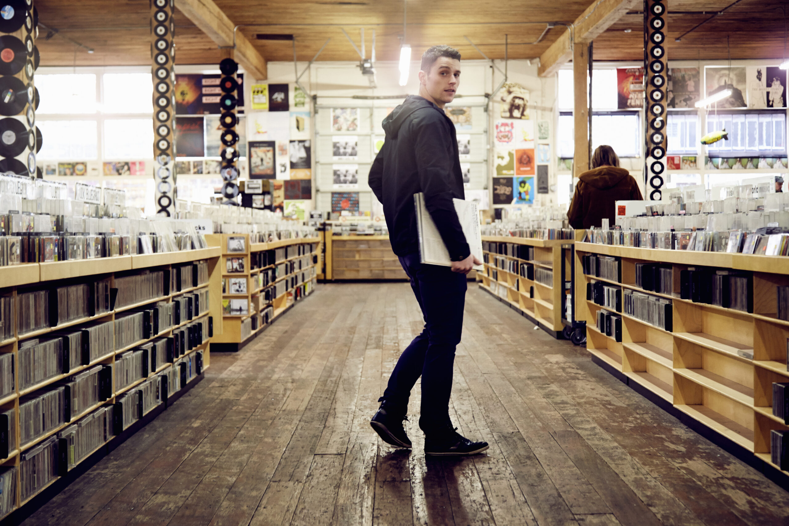 Young Man Holding Vinyl Record In a Music Store
