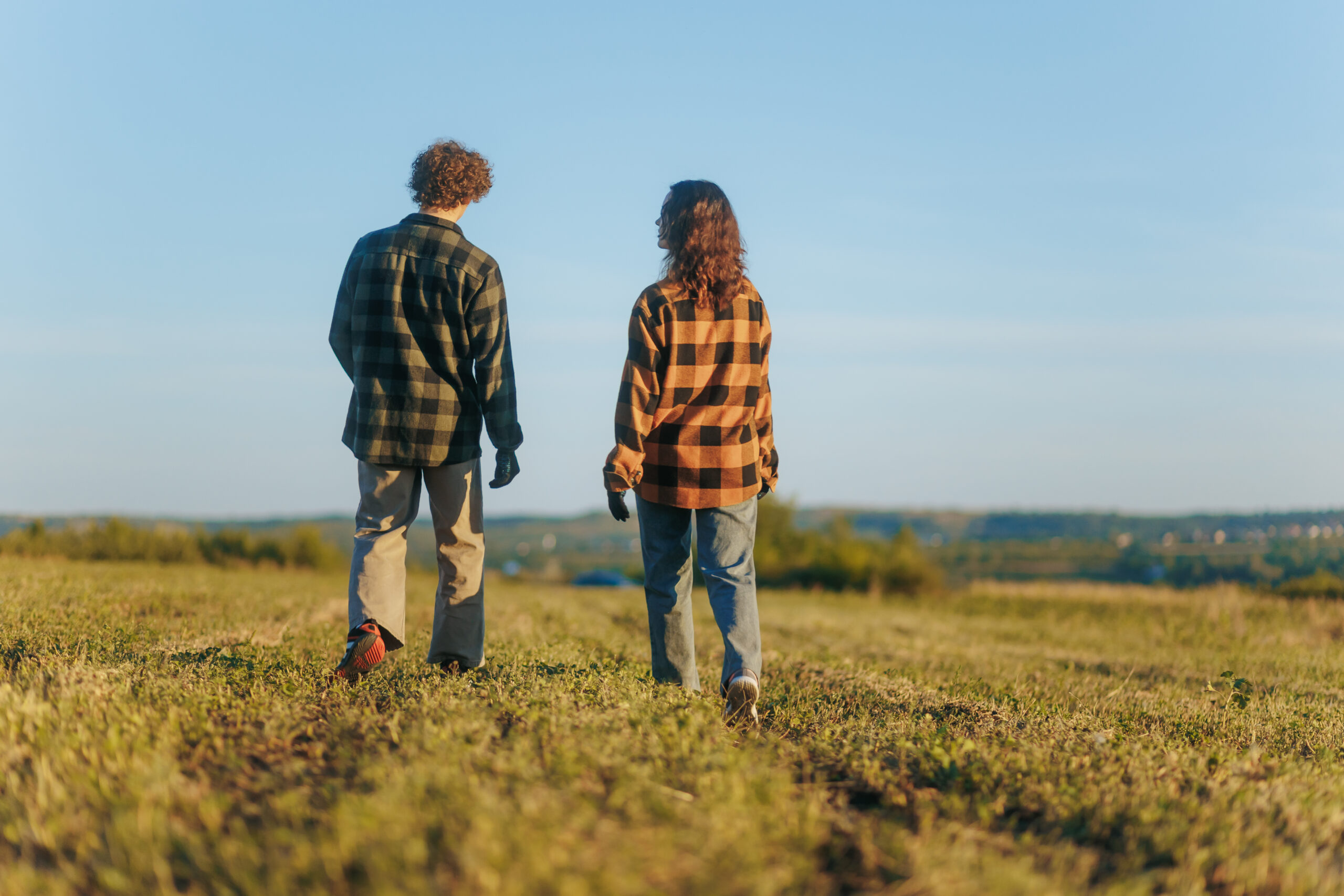 Adults Strolling On A Grassy Hill Under Blue Sky