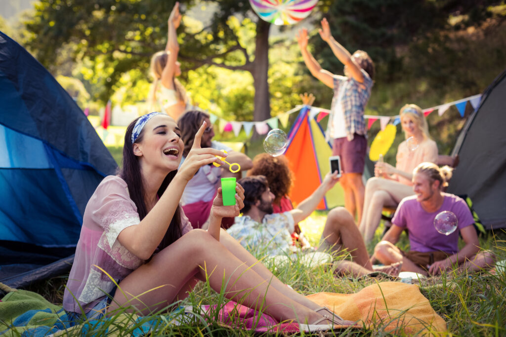 Friends Enjoy Bubbles And Beach Ball At Campsite