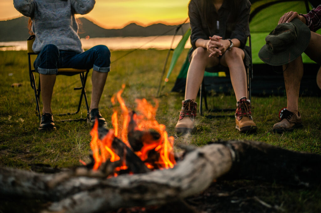 Group of friends camping and sitting around fire.