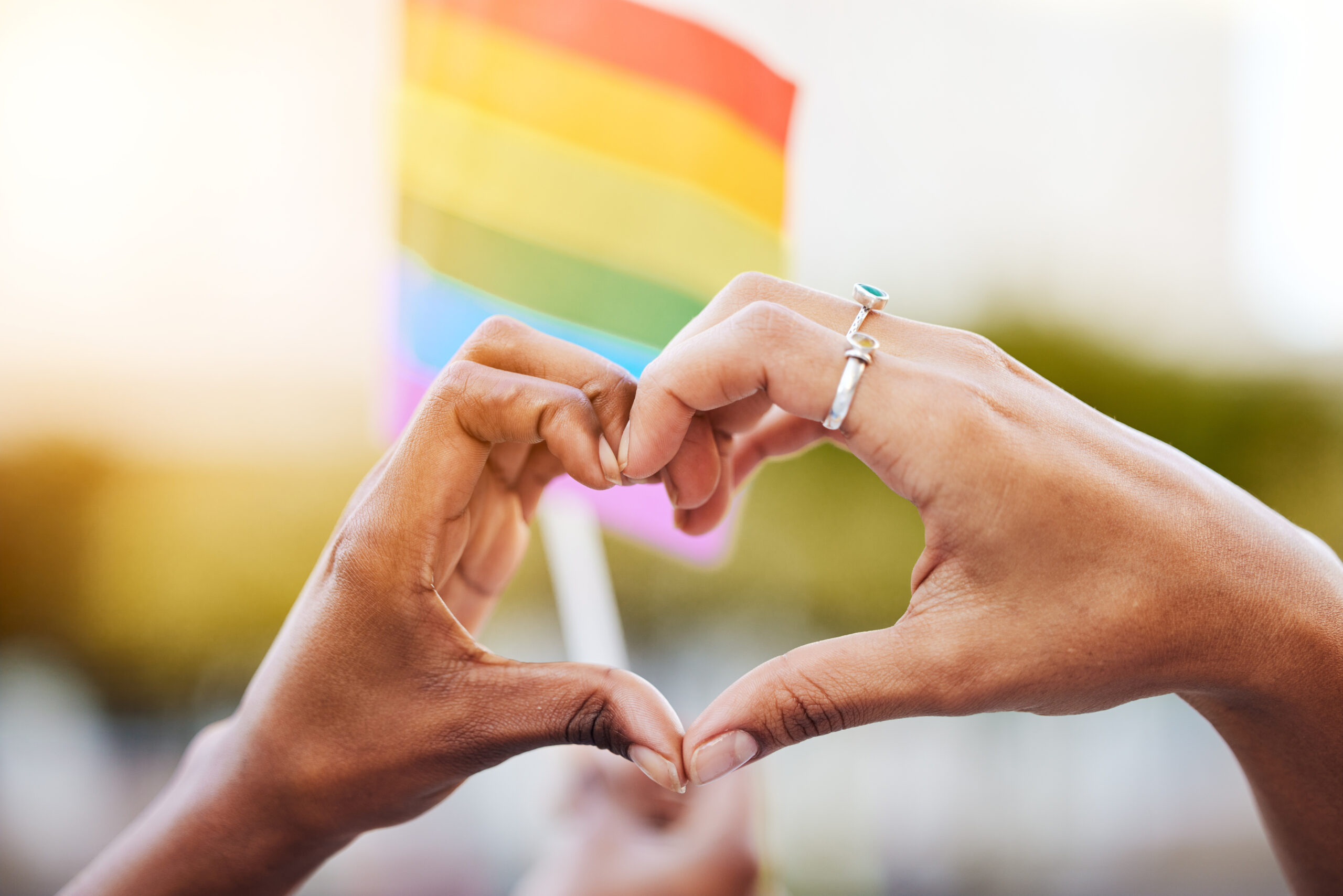 Hands Making Heart Shape In Front Of Pride Flag