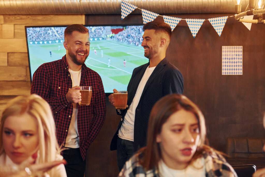 Group of young friends sitting together in bar with beer.